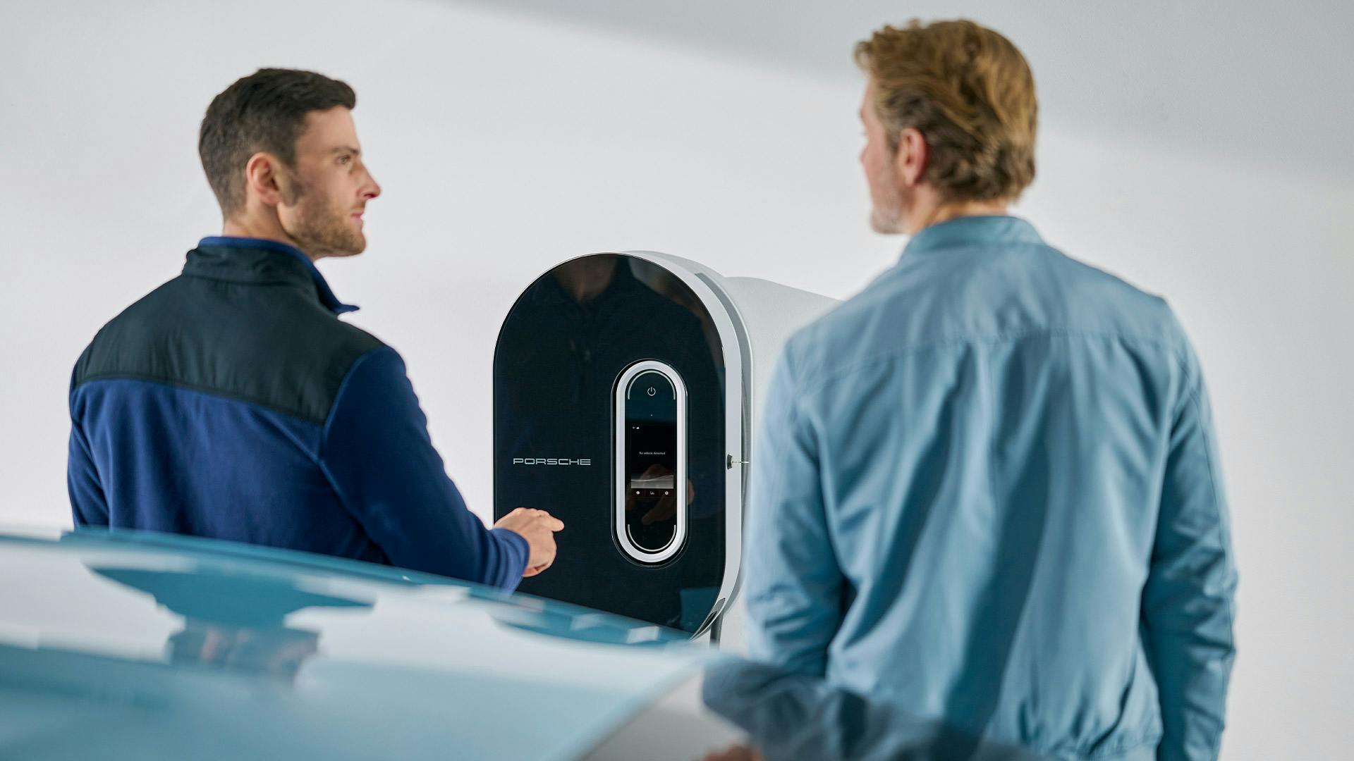 A man opening a Wallbox. A Porsche Taycan Turbo Cross Turismo is in the background.