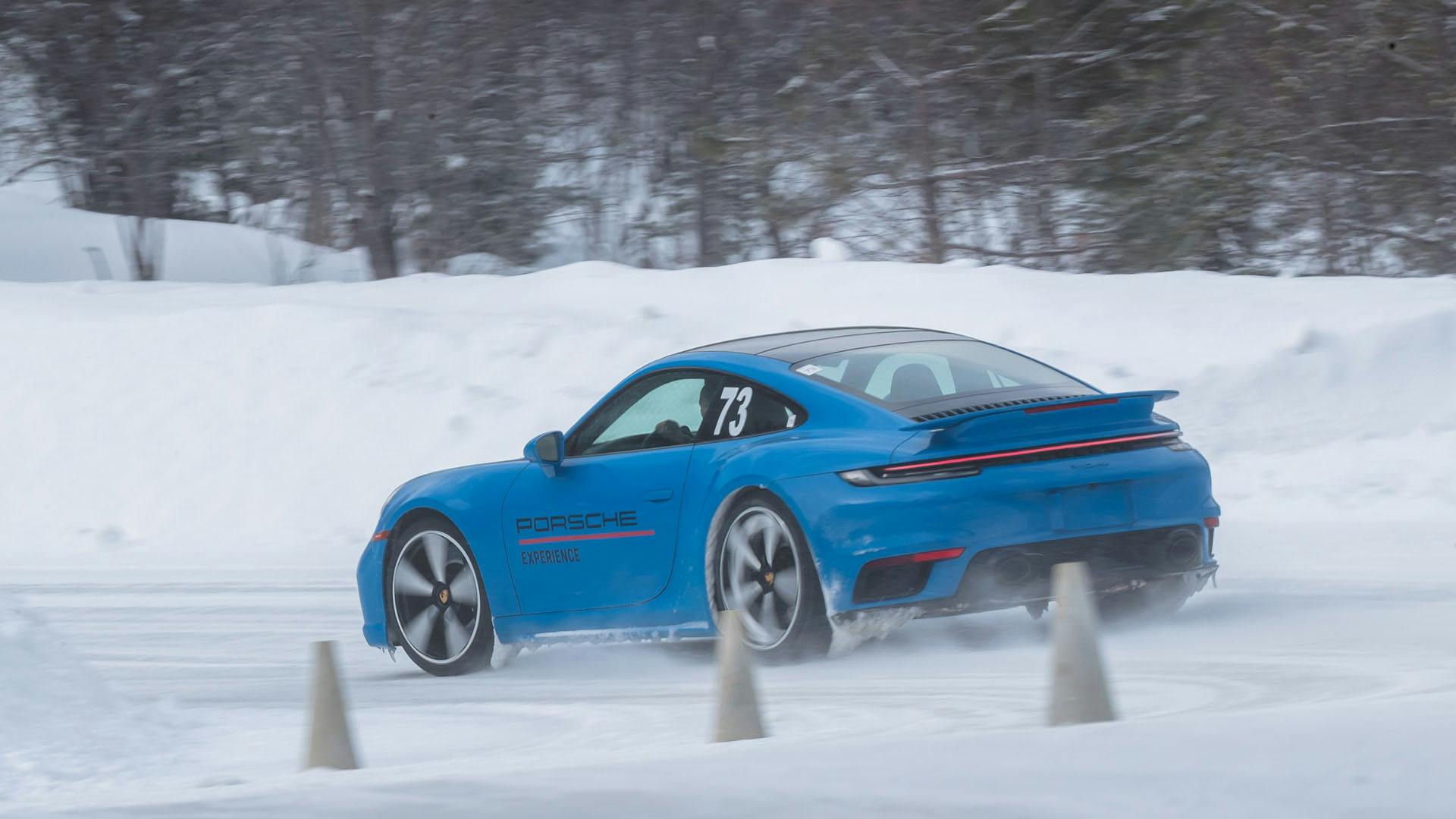 Une Porsche 911 bleue prenant un virage serré sur une piste enneigée.
