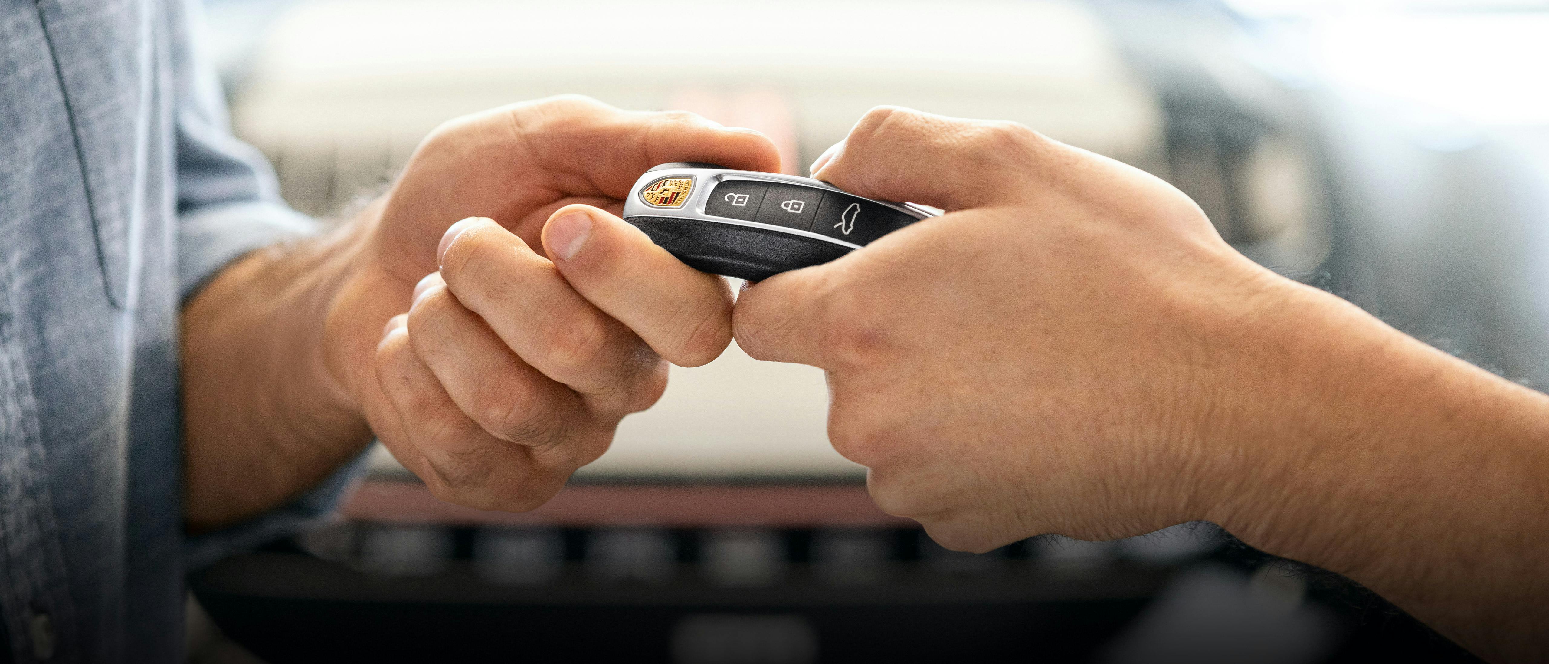 A hand passing along a Porsche key fob.