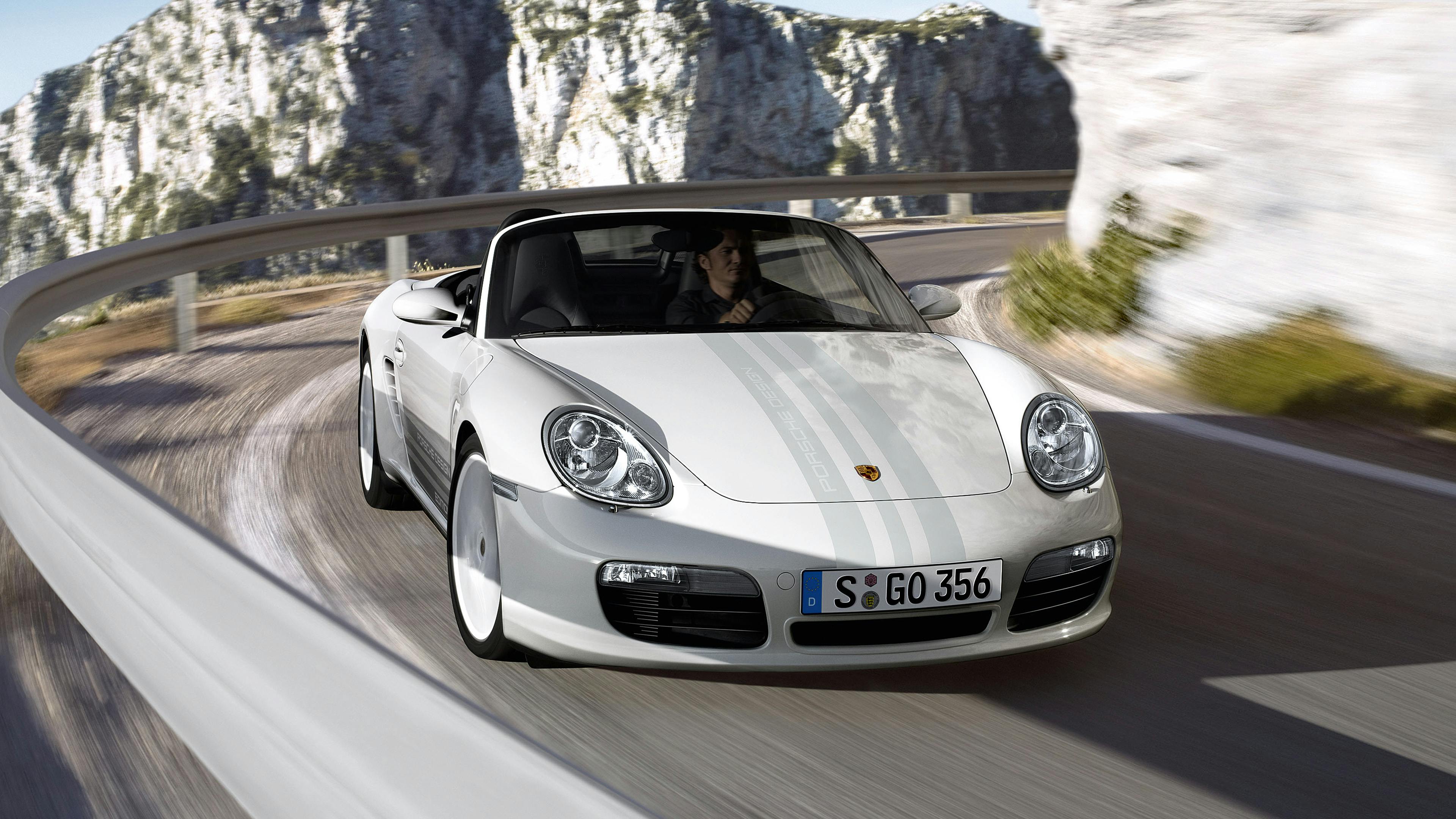 Driving silver Boxster S Porsche Design Edition on a mountain road.