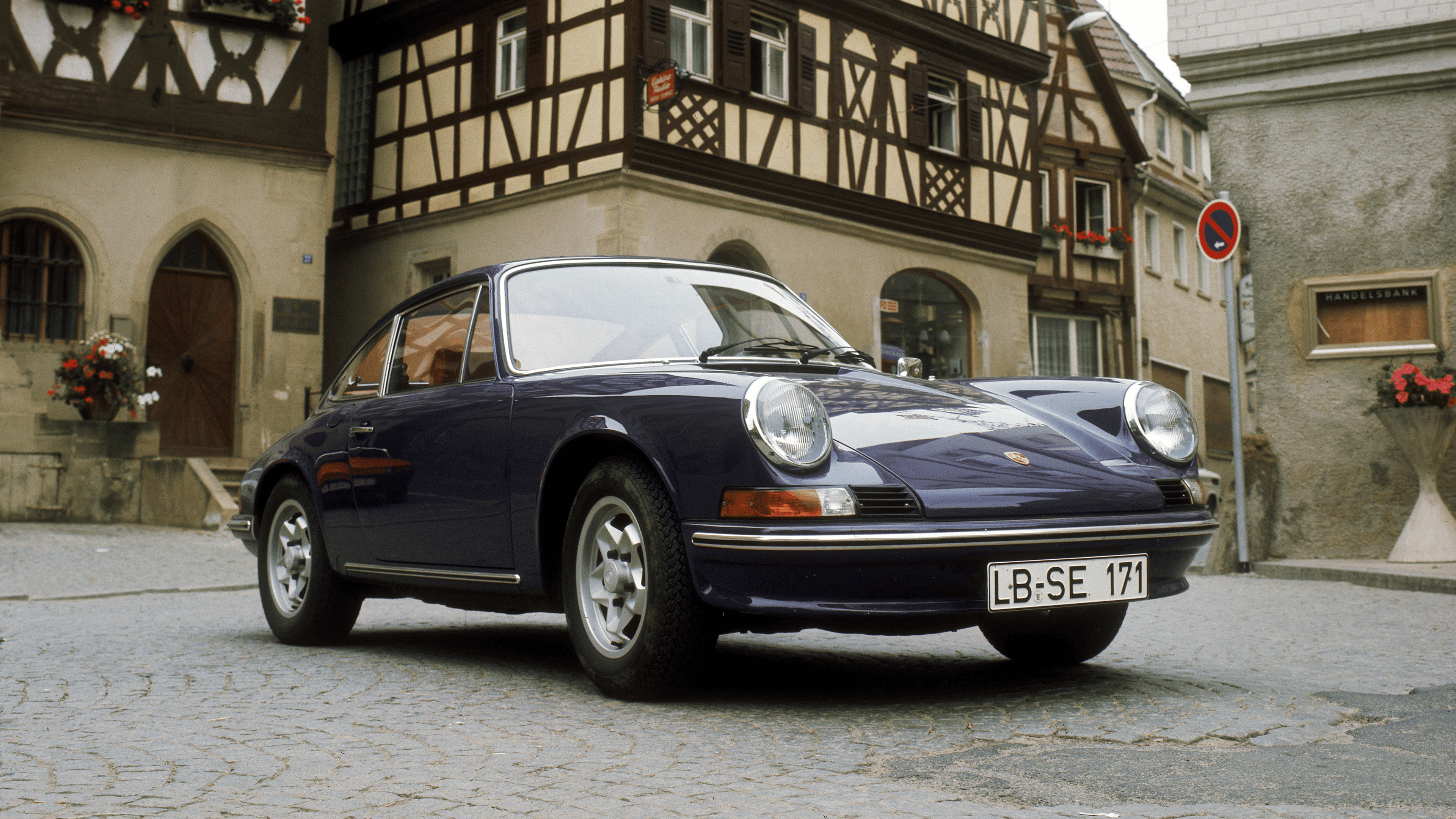 Porsche 911 E 2.4 in dark blue in front of a half-timbered house