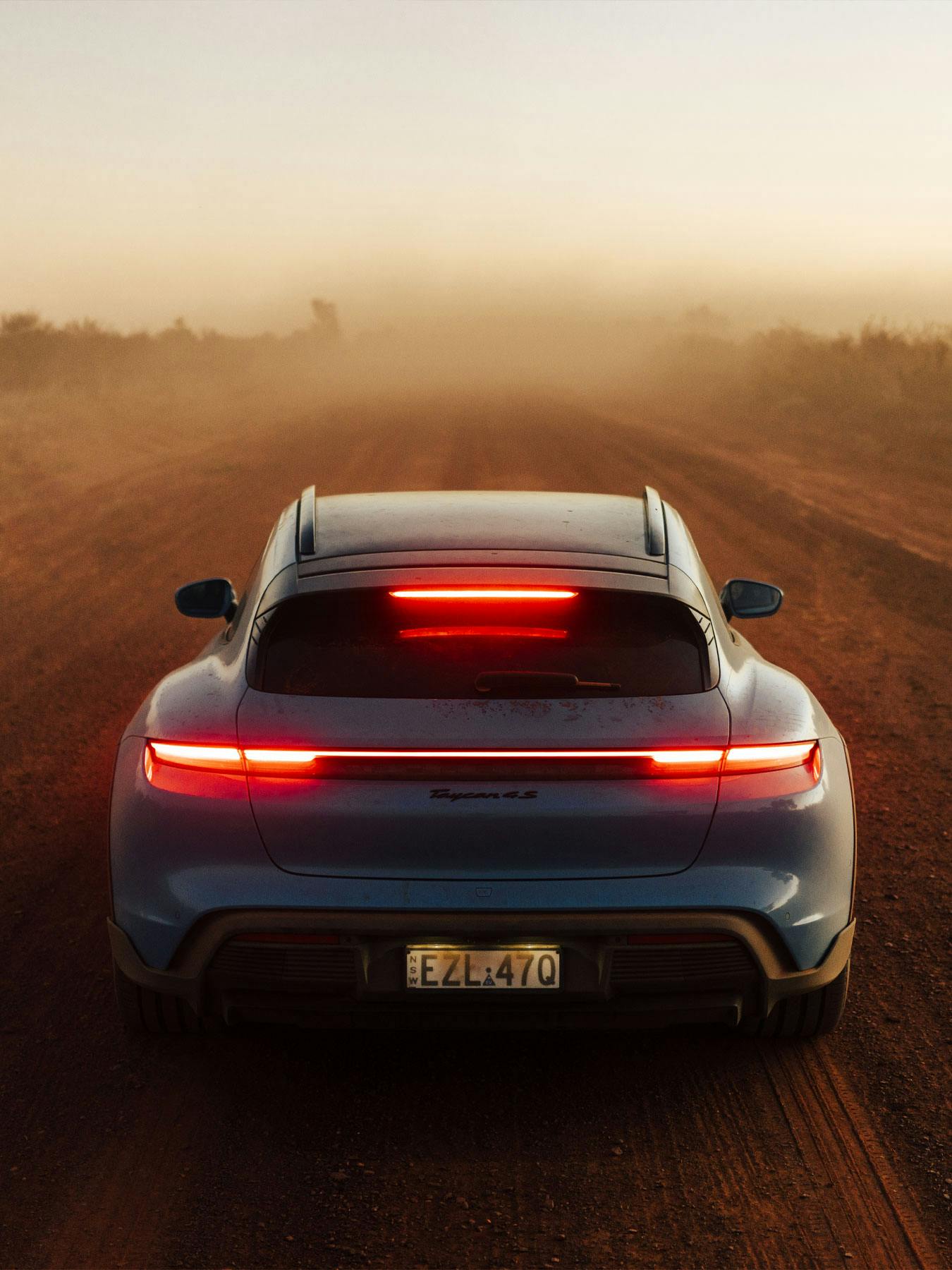 Porsche Taycan driving on a road at sunset