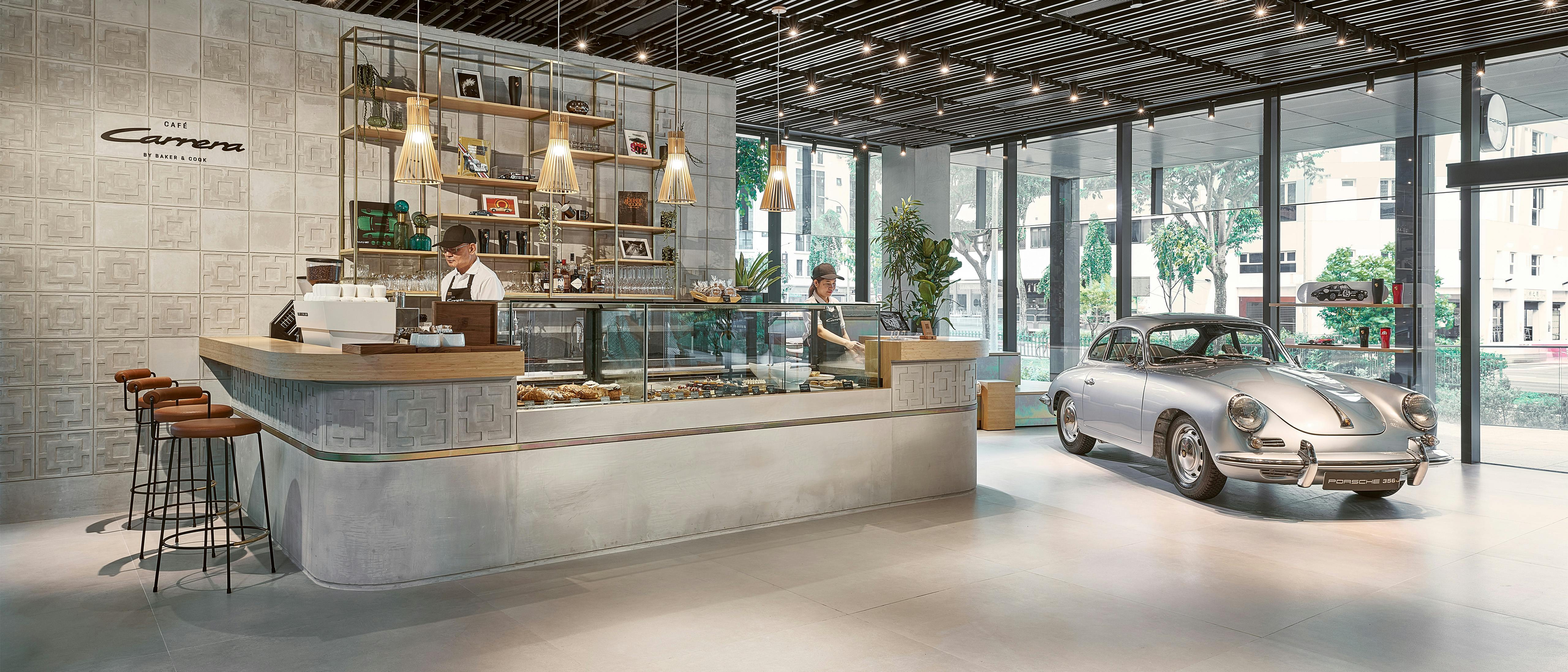 Café Carrera with modern barista counter and silver Porsche 356 as a highlight in a bright showroom.