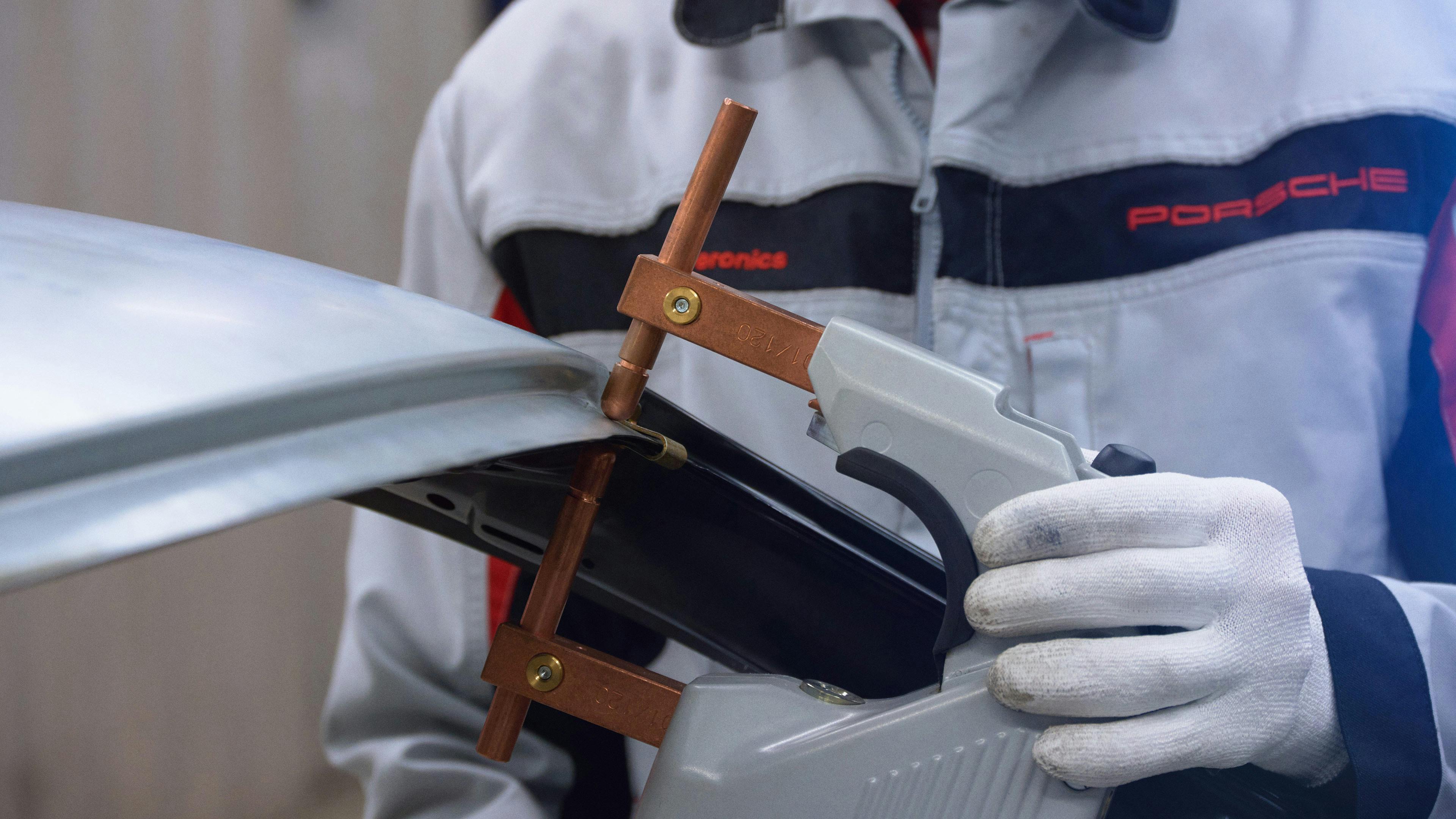 Porsche employee attaches  clamp to the body-in-white.