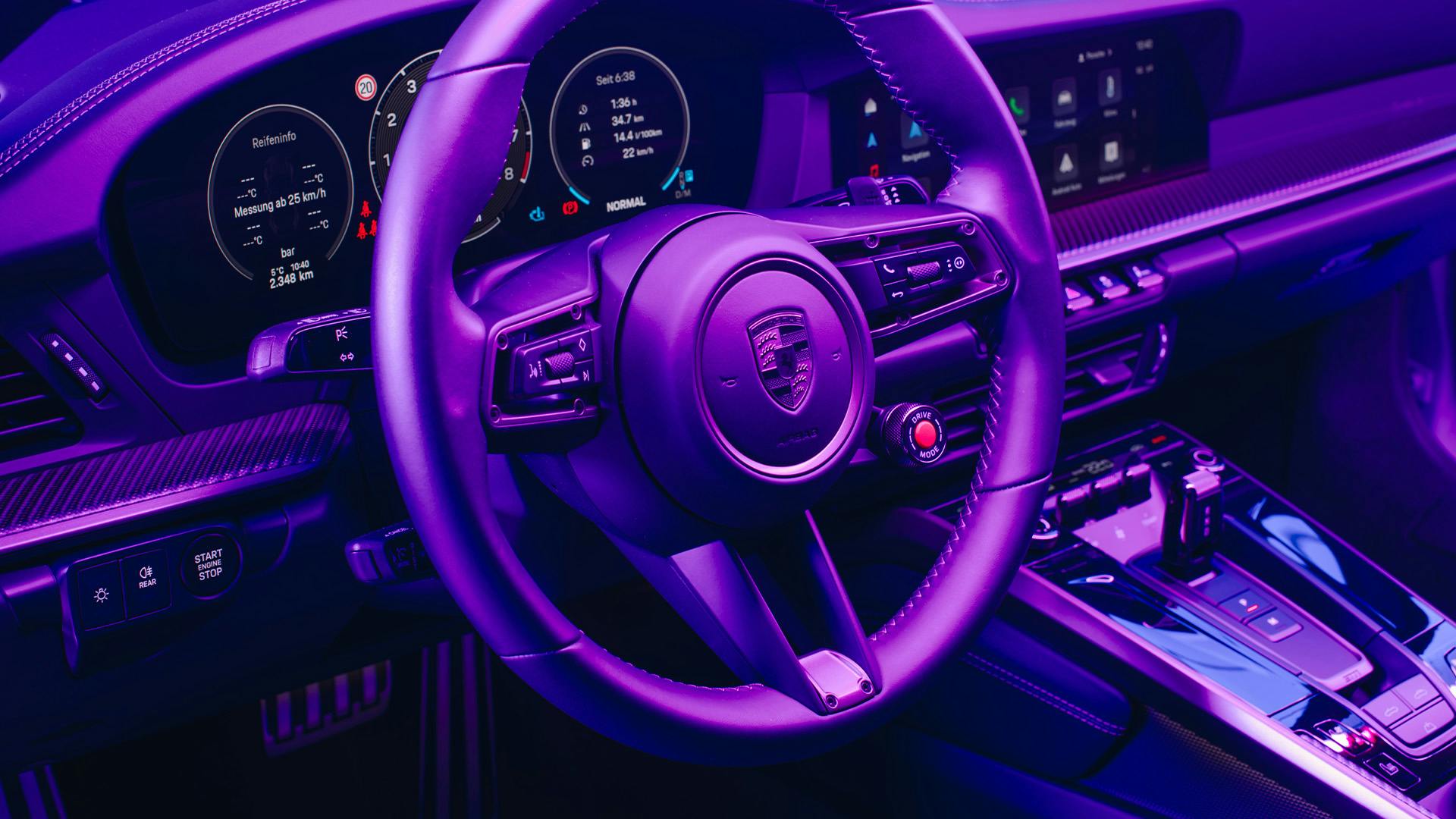 Das Lenkrad und Kombiinstrument eines Porsches in der Nahaufnahme in futuristischem Licht.