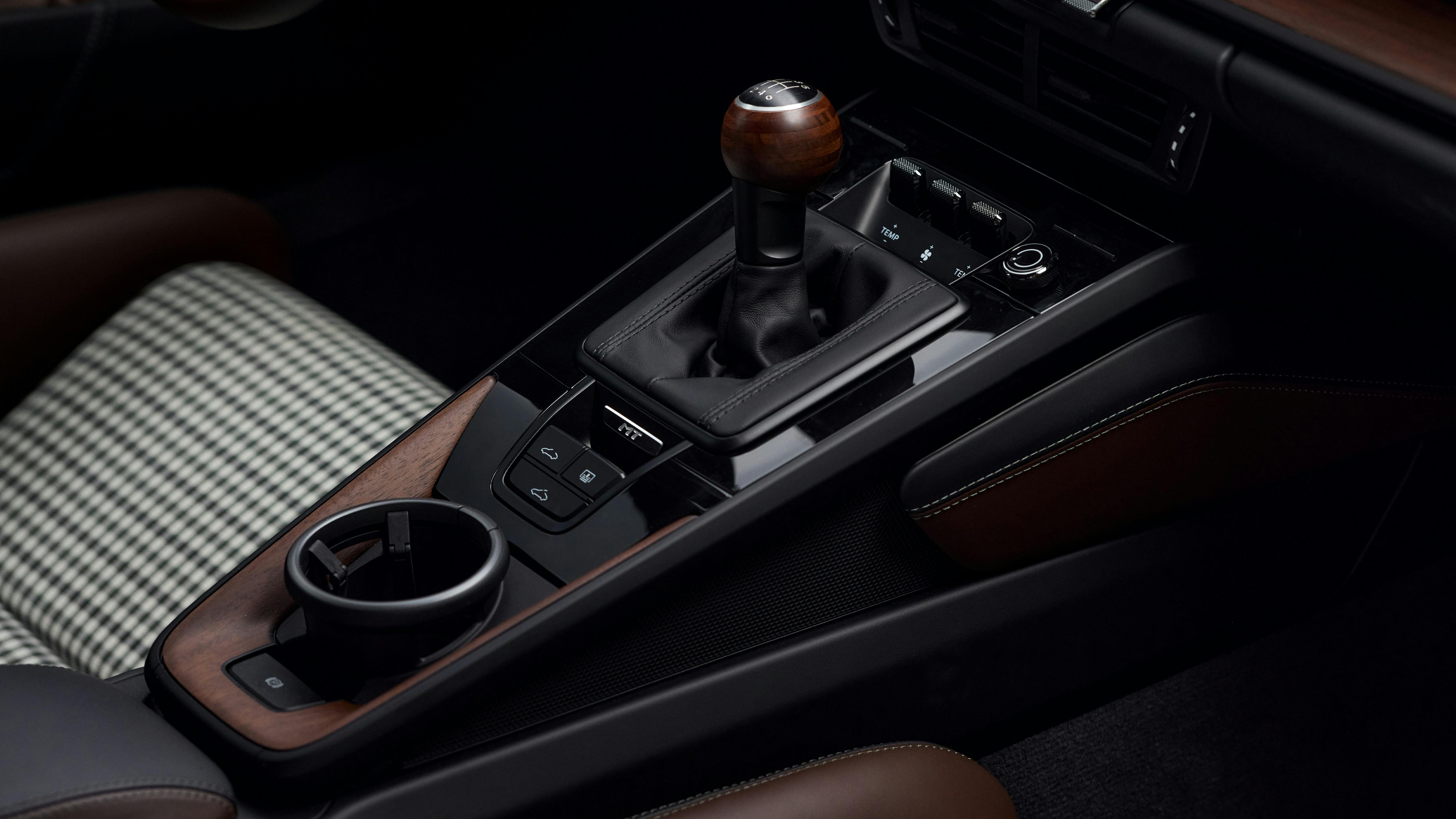 Detail of a Porsche 911 Carrera center console with manual gear lever, cup holder and control buttons.