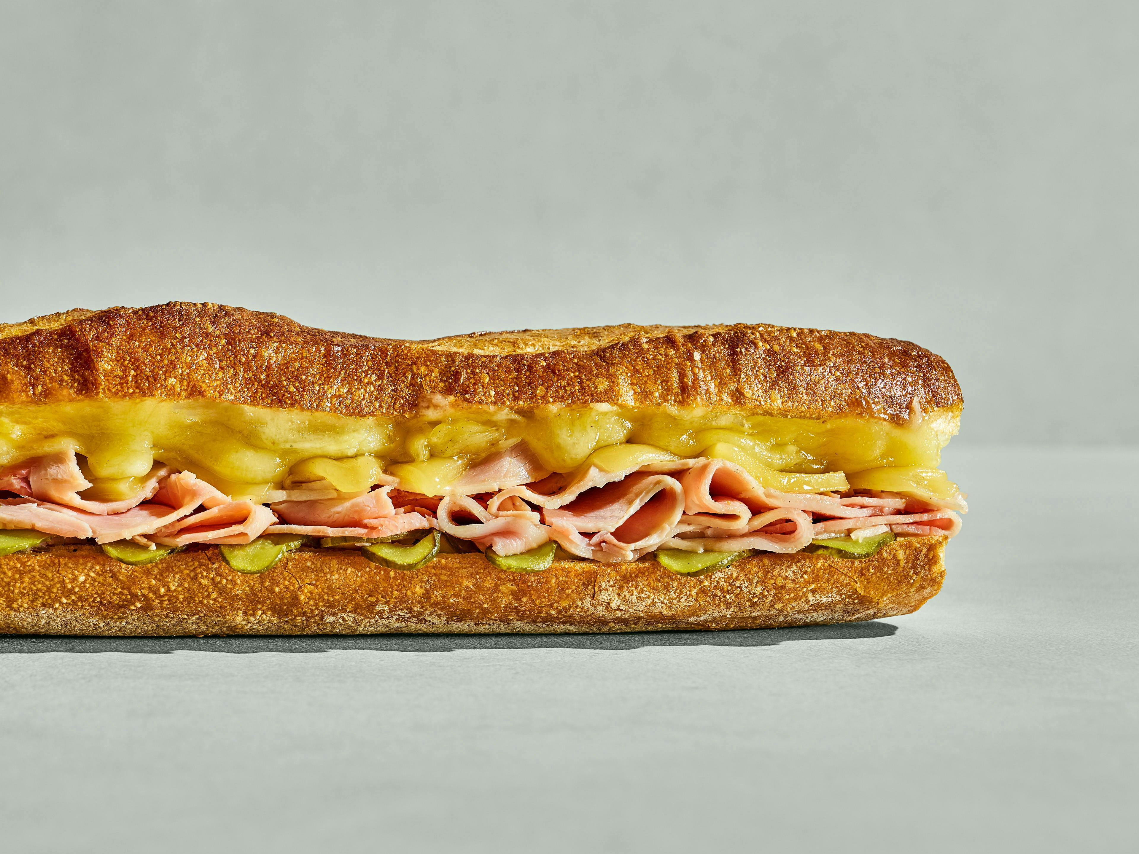 Baguette sandwich filled with ham, pickles and melted cheese.