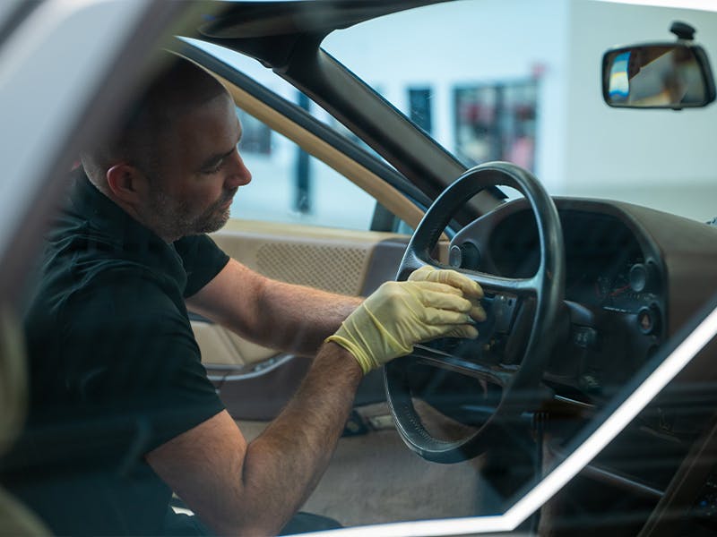 Employee of the factory restoration working on the interior of a classic Porsche.