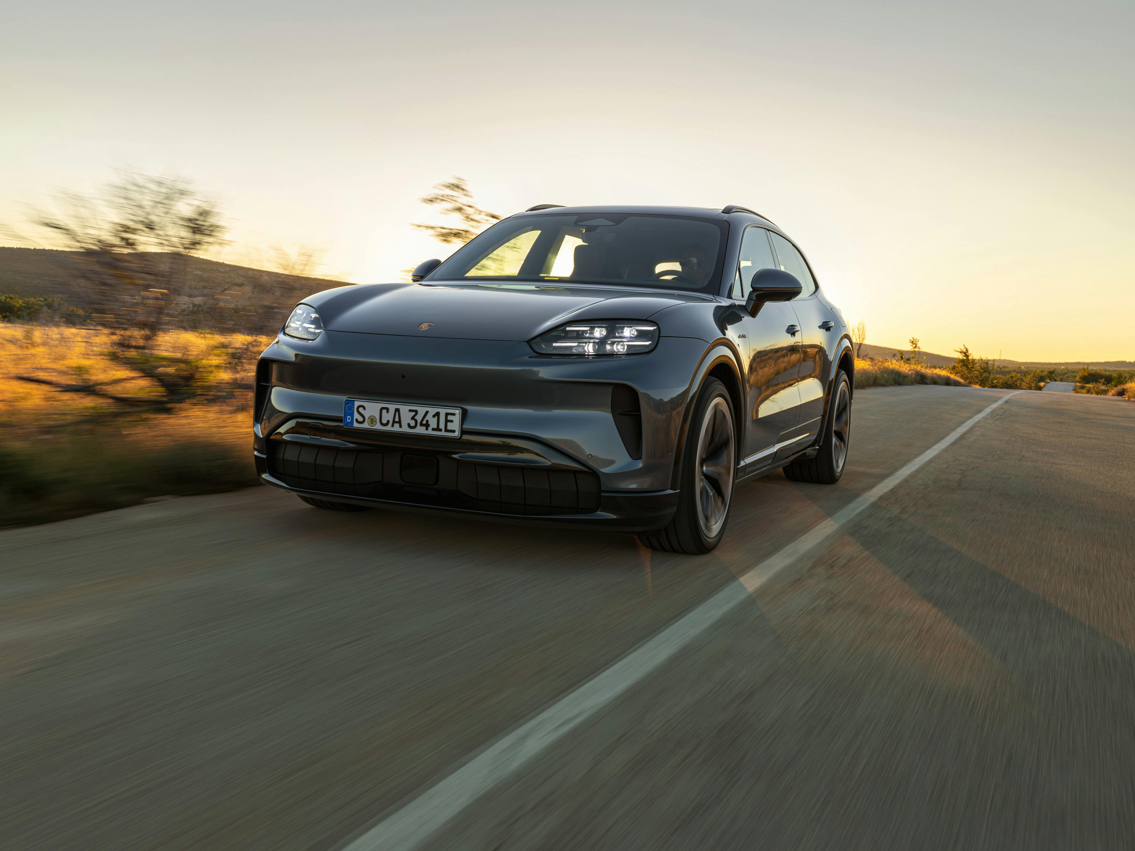 The Cayenne Electric driving along a road, with the sky glowing as the sun rises.