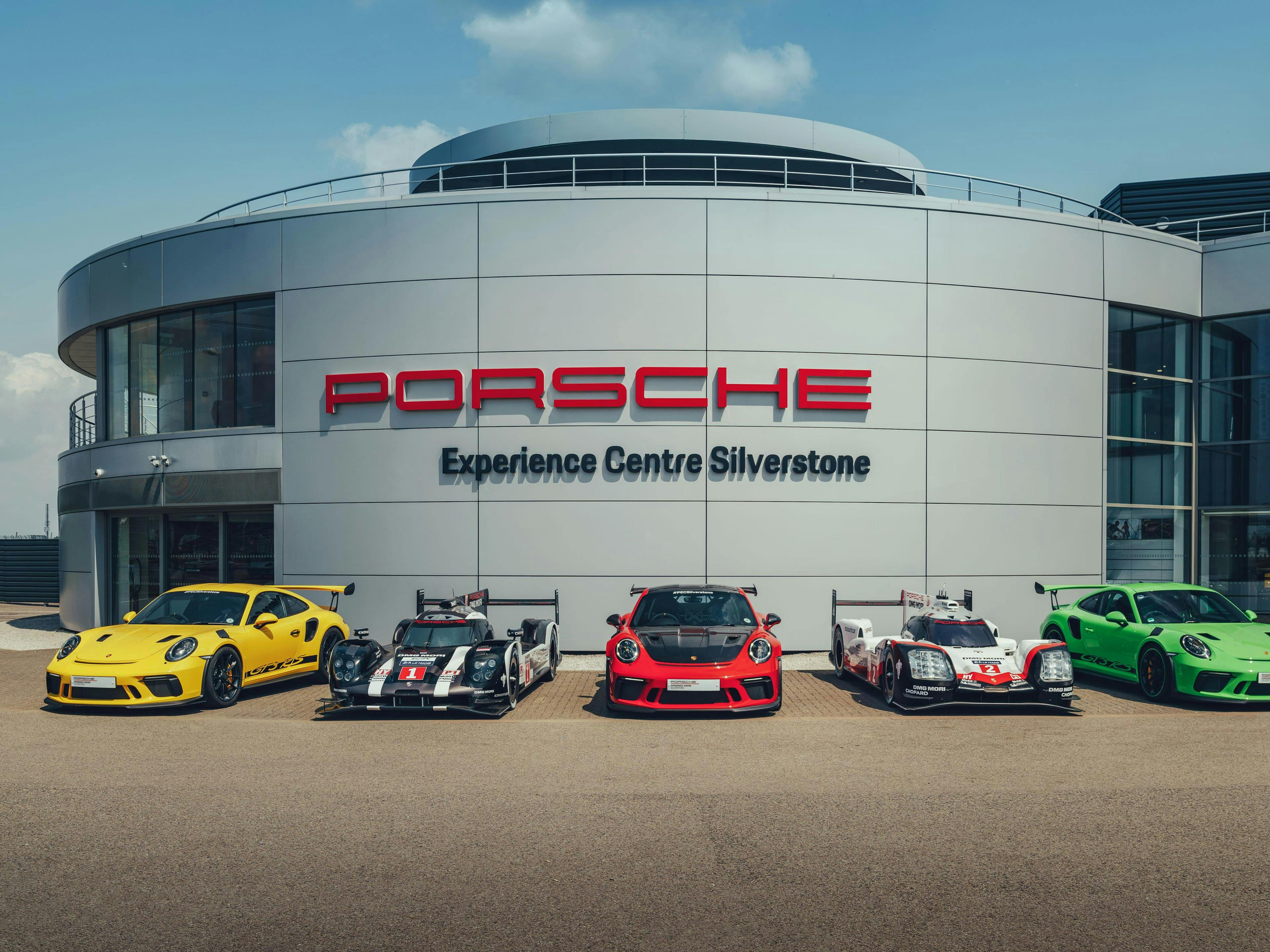 Cinco modelos Porsche, alineados como en una galería, delante del cartel del Porsche Experience Center Silverstone.