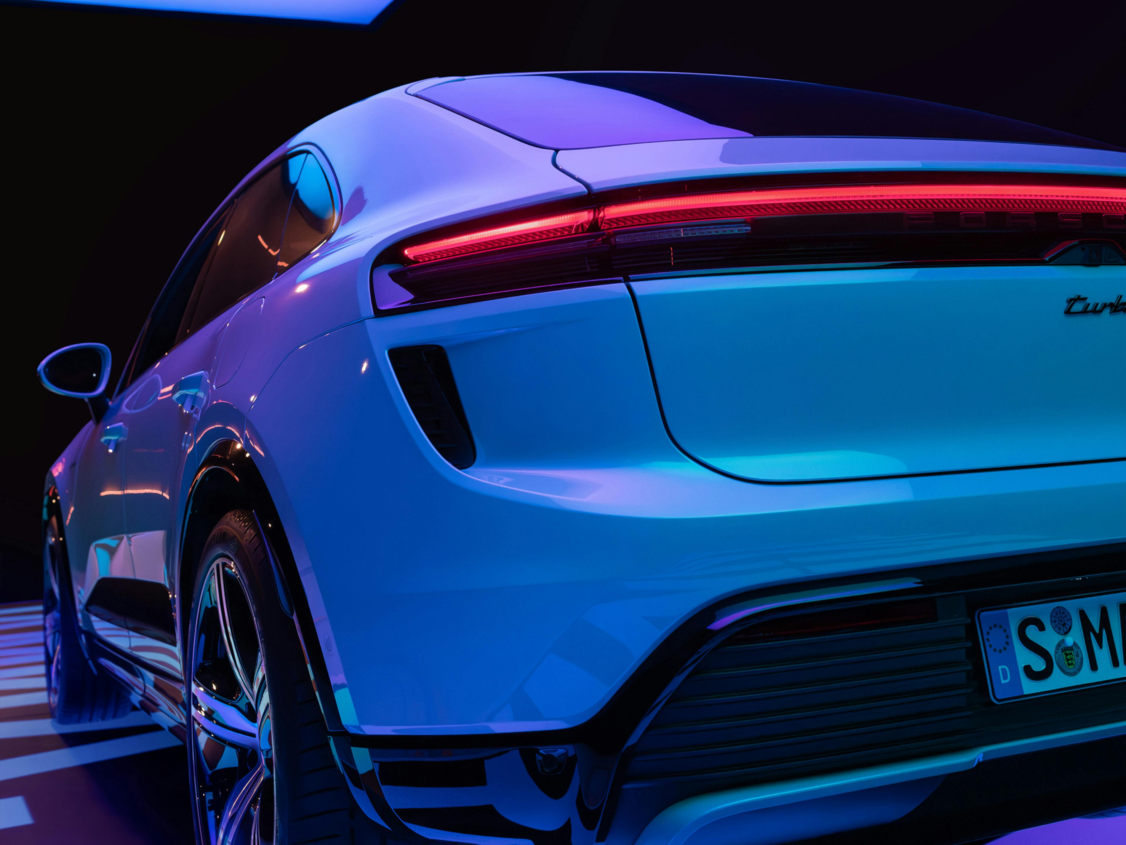 Rear quarter of Porsche Macan in purple studio lighting.