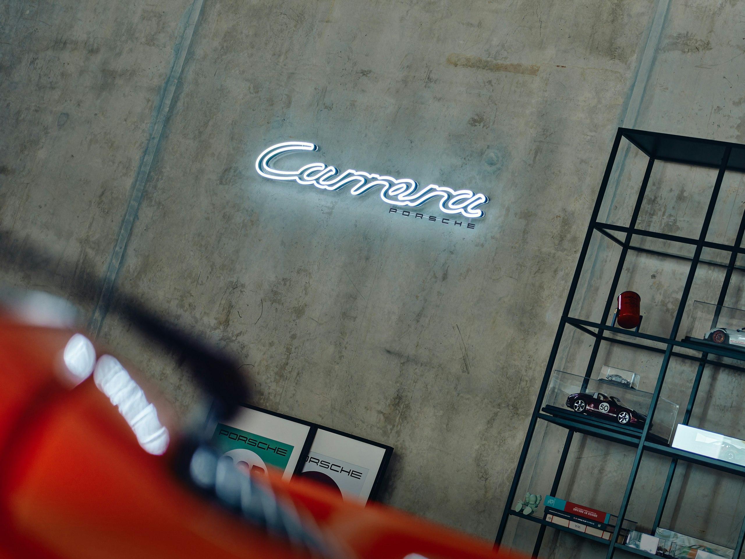 Neon sign on a concrete wall reading Carrera Porsche