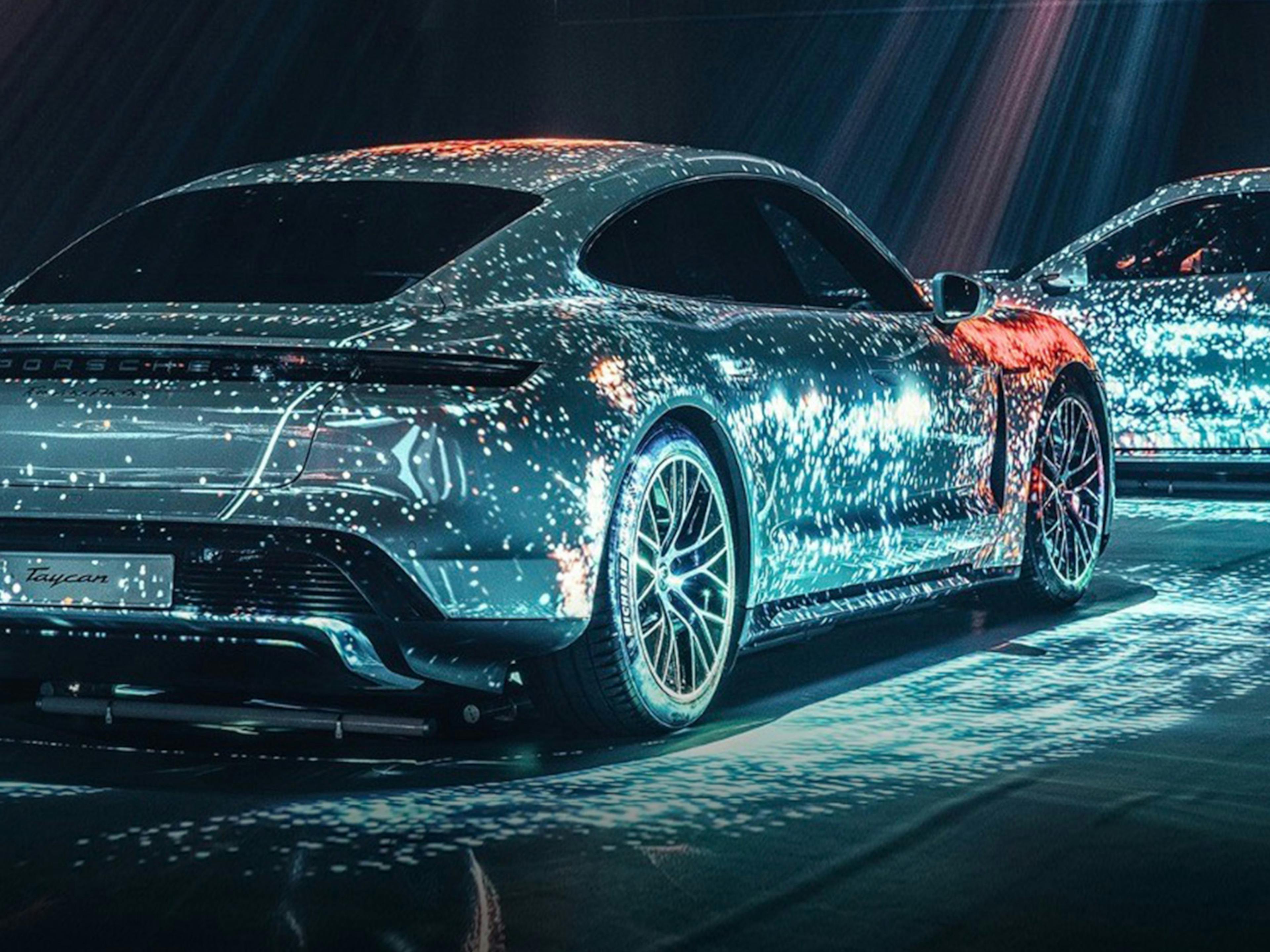 Mehrere Porsche Taycan, die in einer futuristischen Lichtwelt in Szene gesetzt werden.