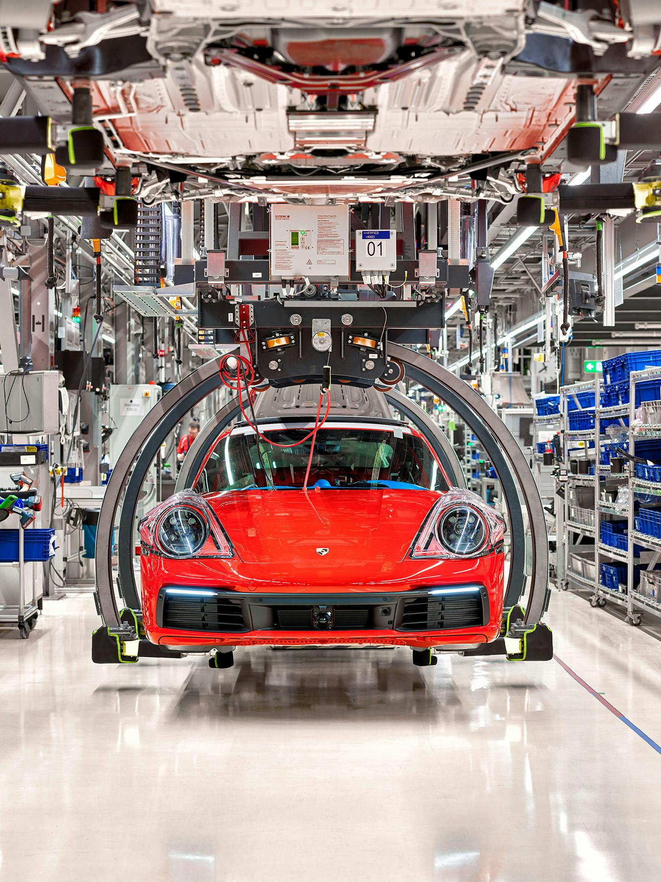 A red Porsche 911 being built on a vehicle assembly line.