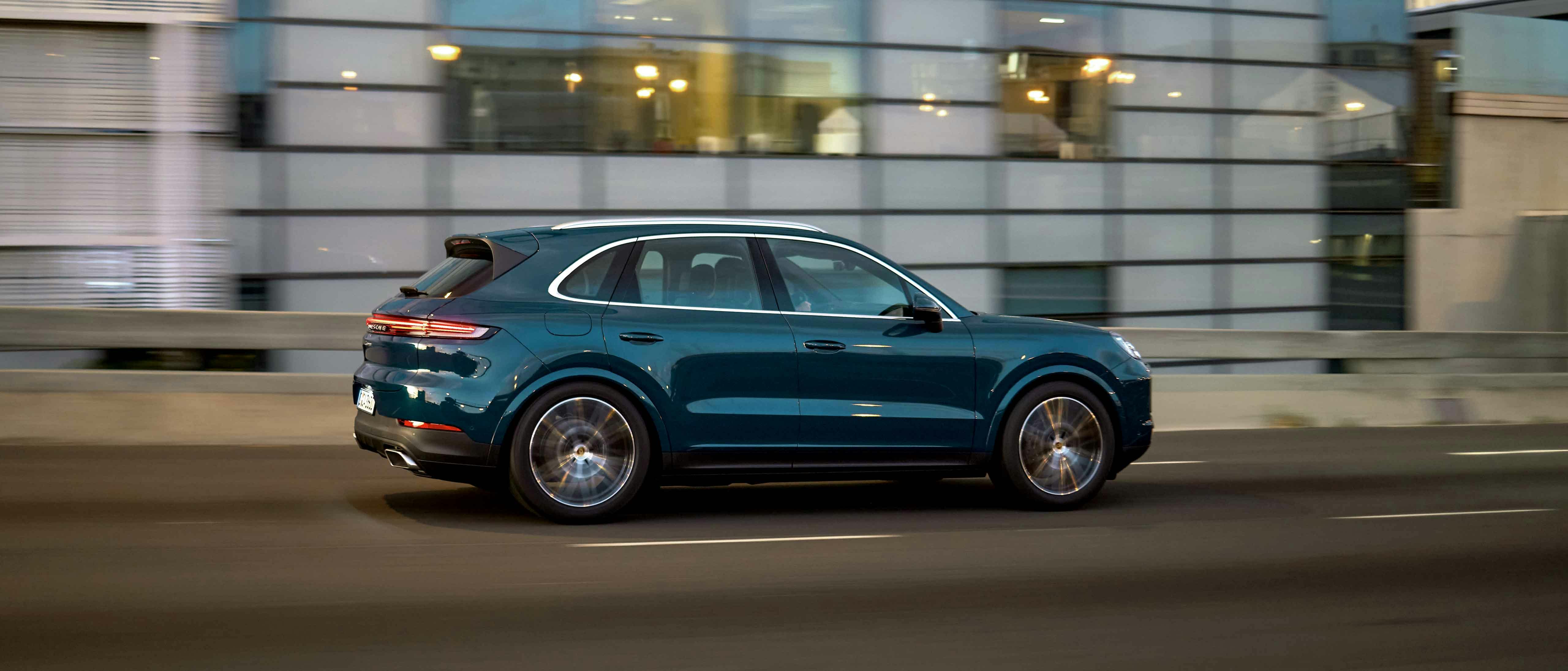 En blå Porsche Cayenne kör på en gata genom staden.