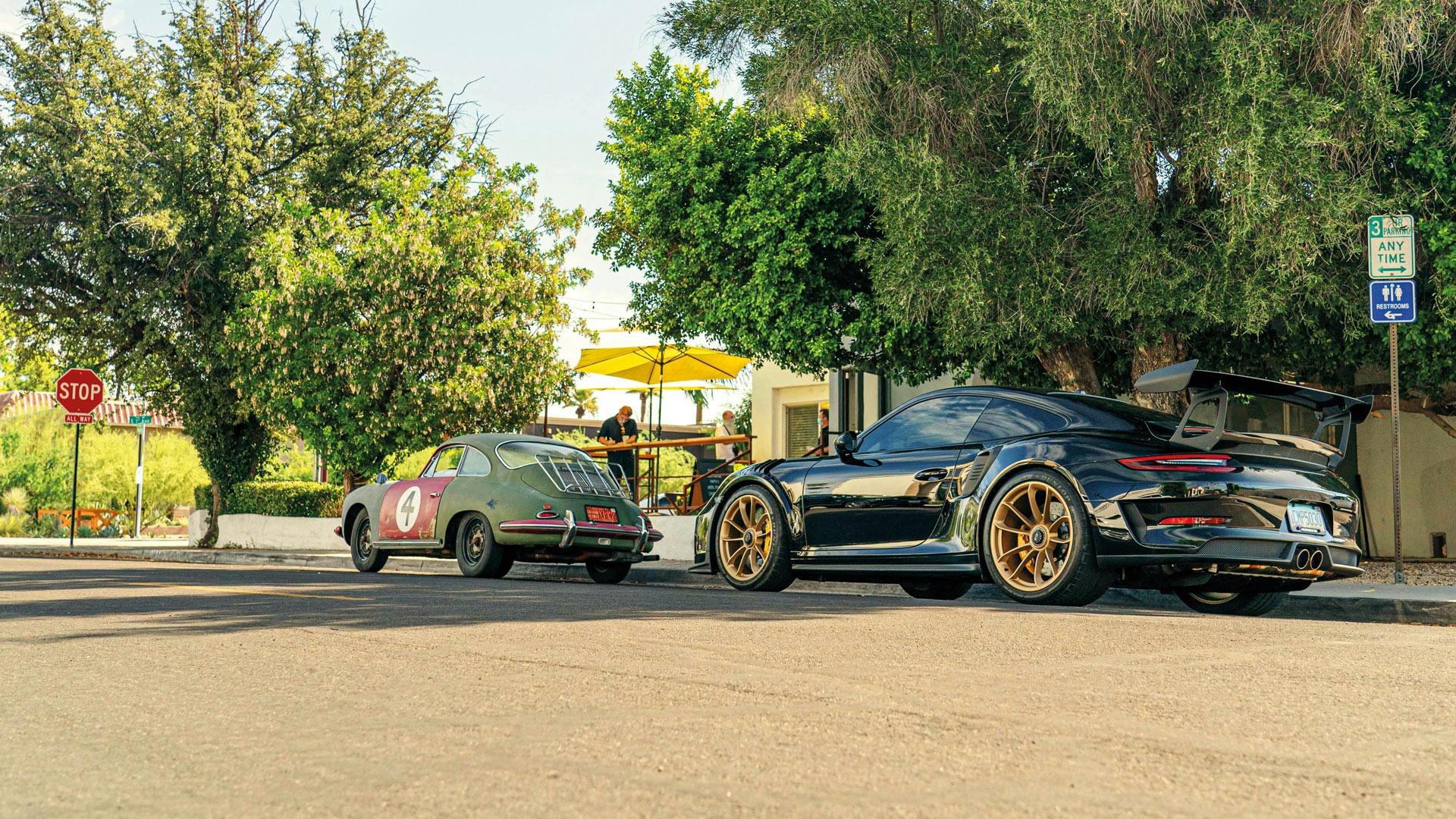 Ein morderner Porsche und ein Oldtimer Porsche, die am Straßenrand parken