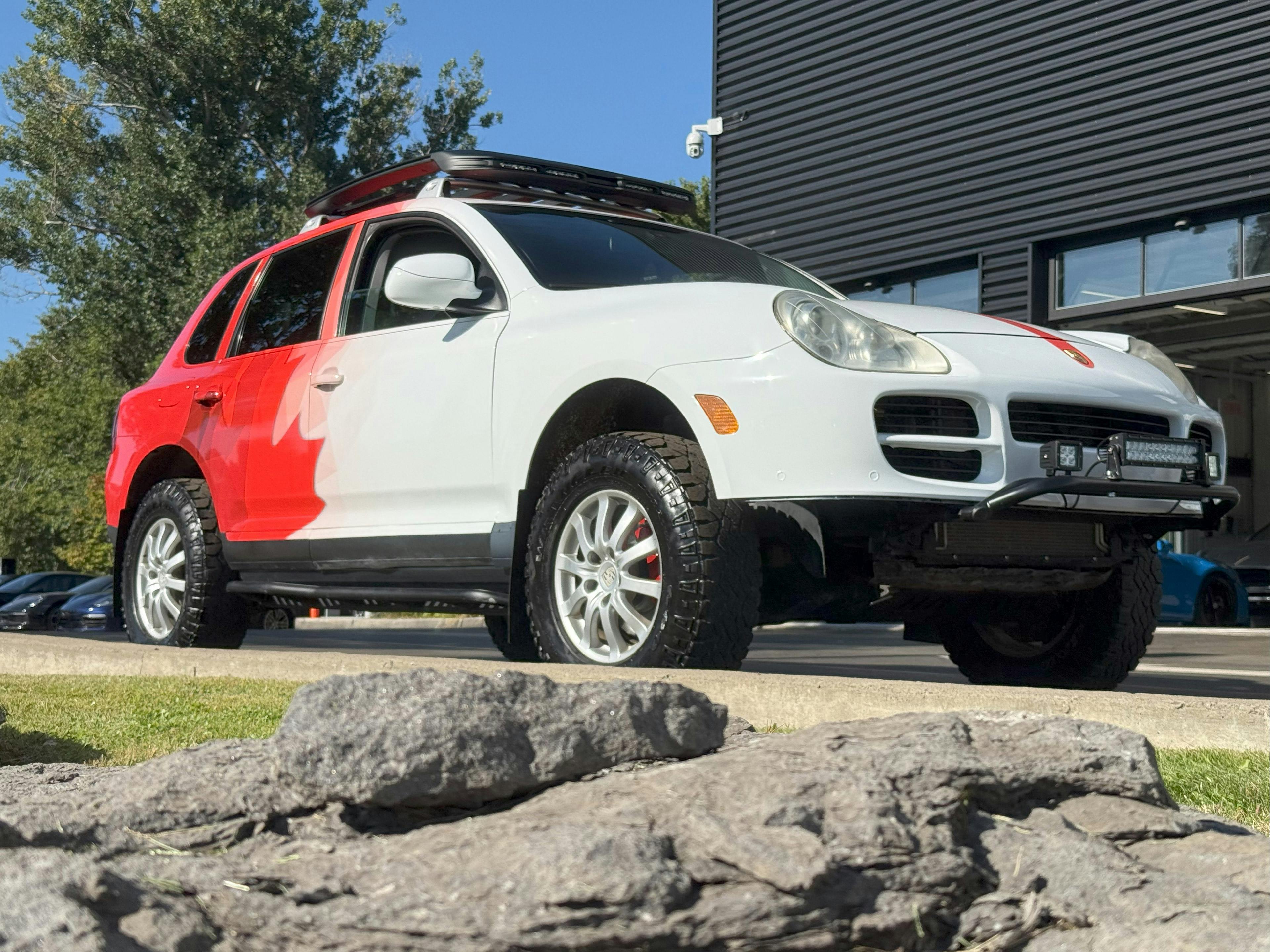 Prestige – A black Porsche Cayenne elevated in a service bay.