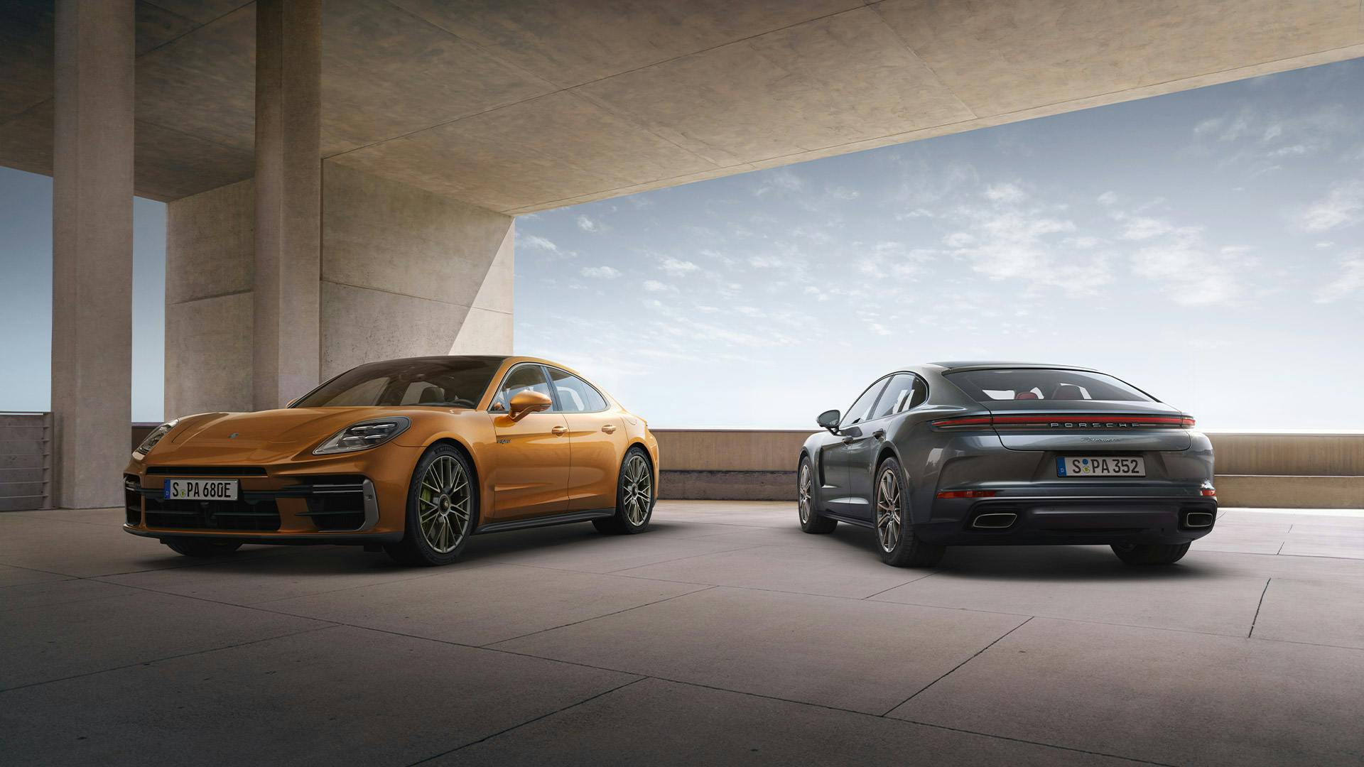 Ein goldener und ein schwarzer Porsche Panamera stehen unter einer modernen Betondecke.