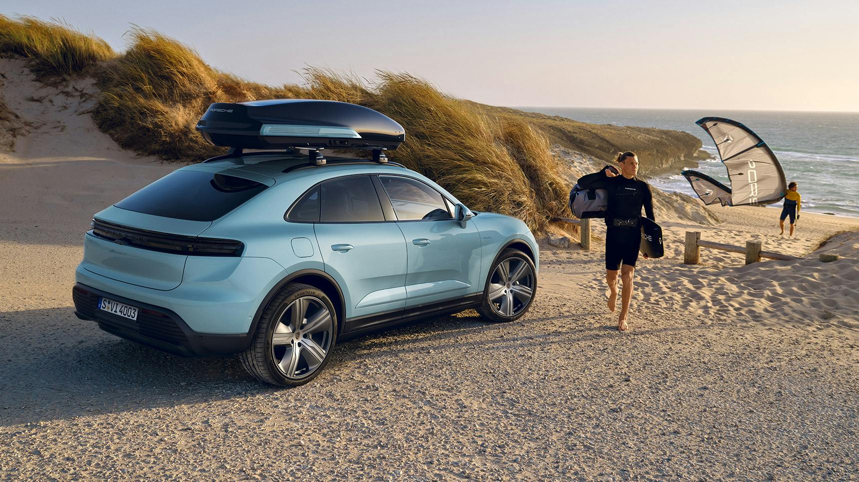 Rear view of a Porsche Macan 4 with Porsche Performance roof box in Black (high-gloss) with blades in exterior colour.