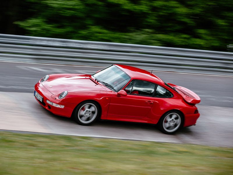 Red Porsche 993 in motion, street scene.