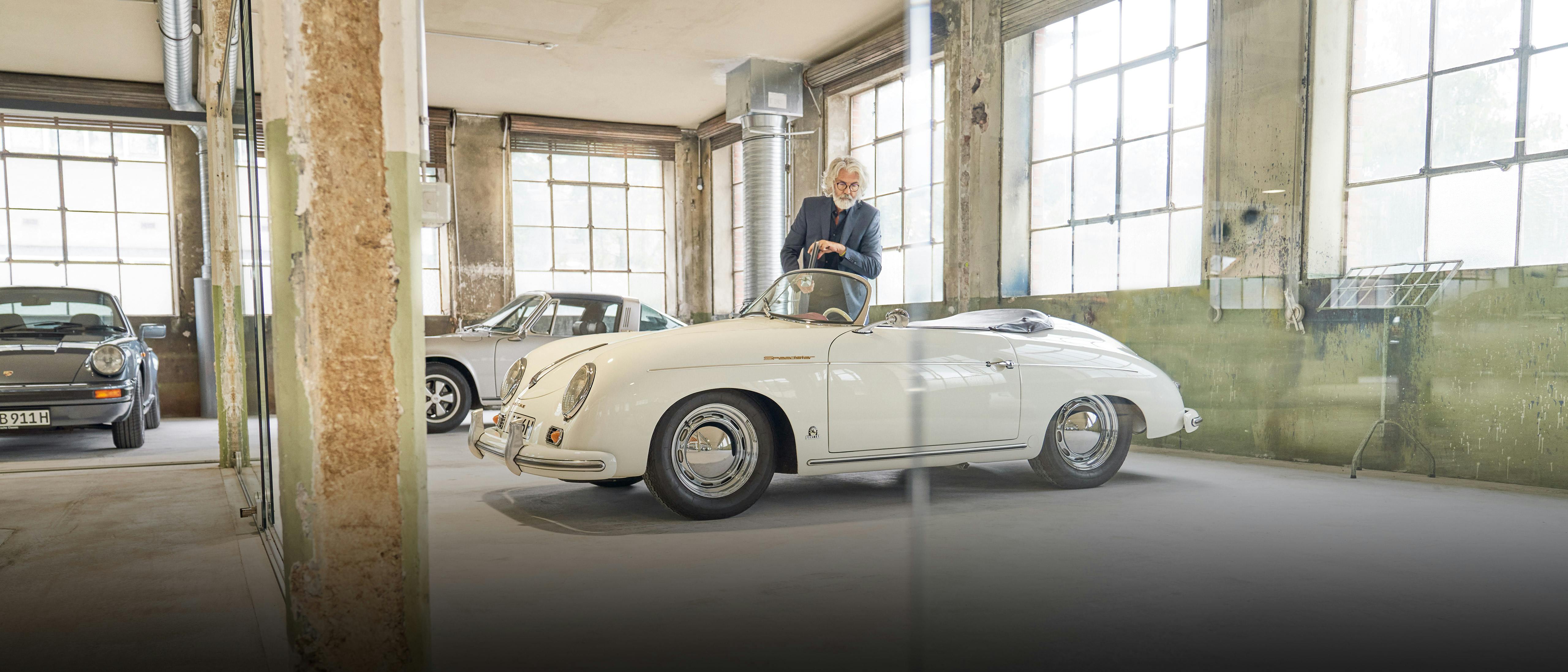 Een man loopt in een ruimte met verschillende Porsche classic modellen