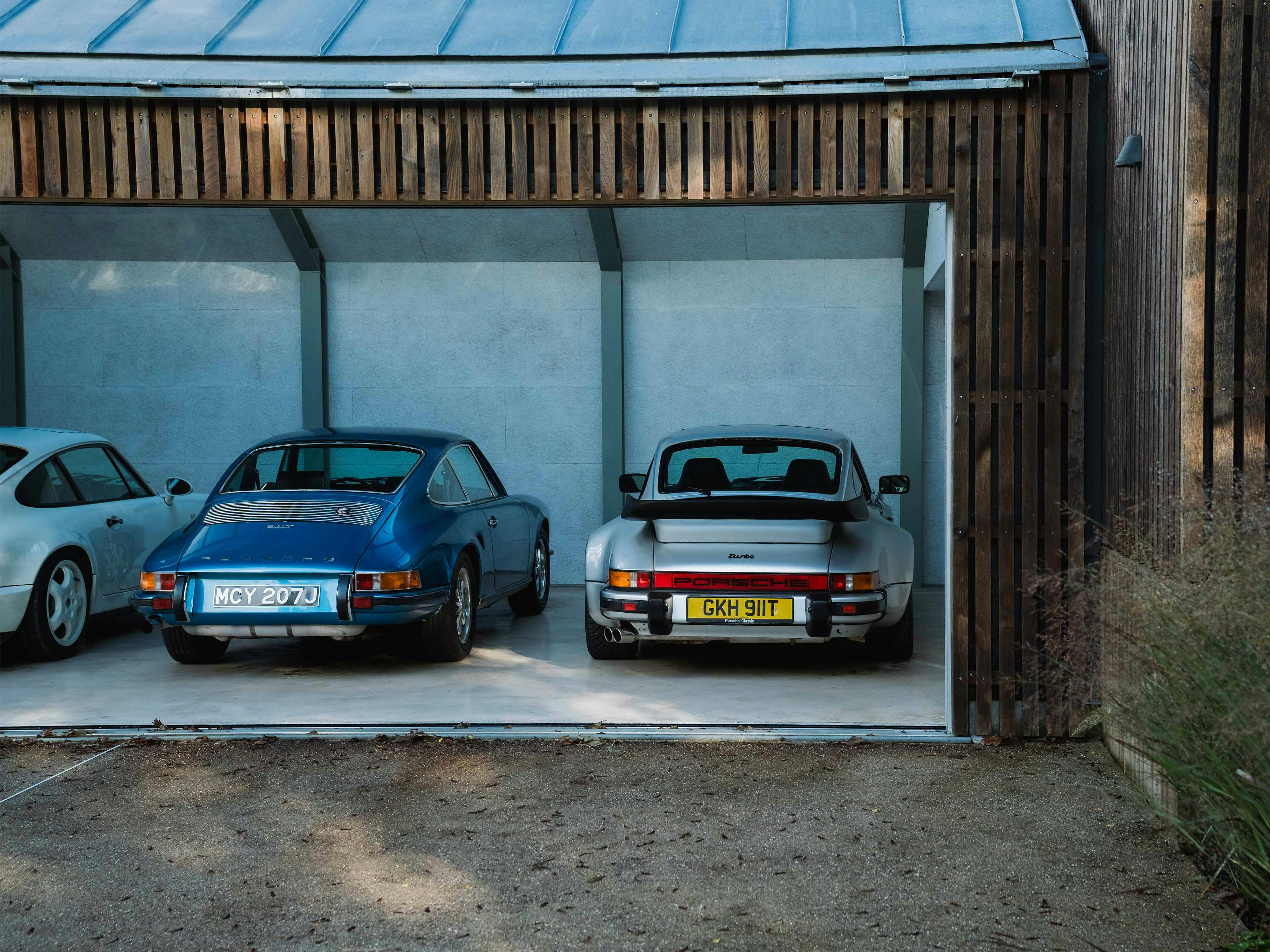 Verschillende Porsche modellen naast elkaar onder een overkapping.