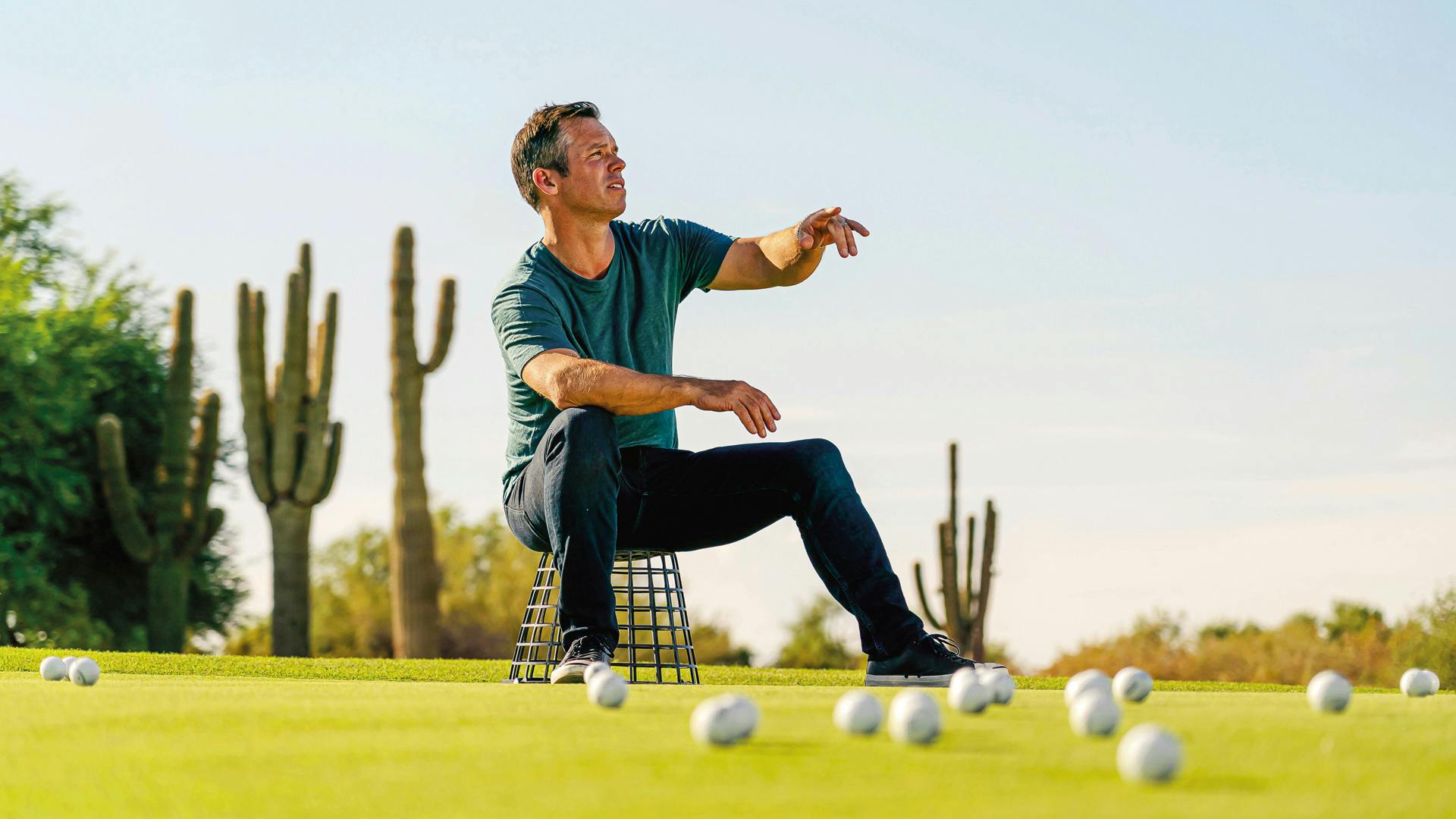 Paul Casey sitzt auf einem umgedrehten Bällekorb auf einem Golfplatz mit mehreren verteilten Golfbällen