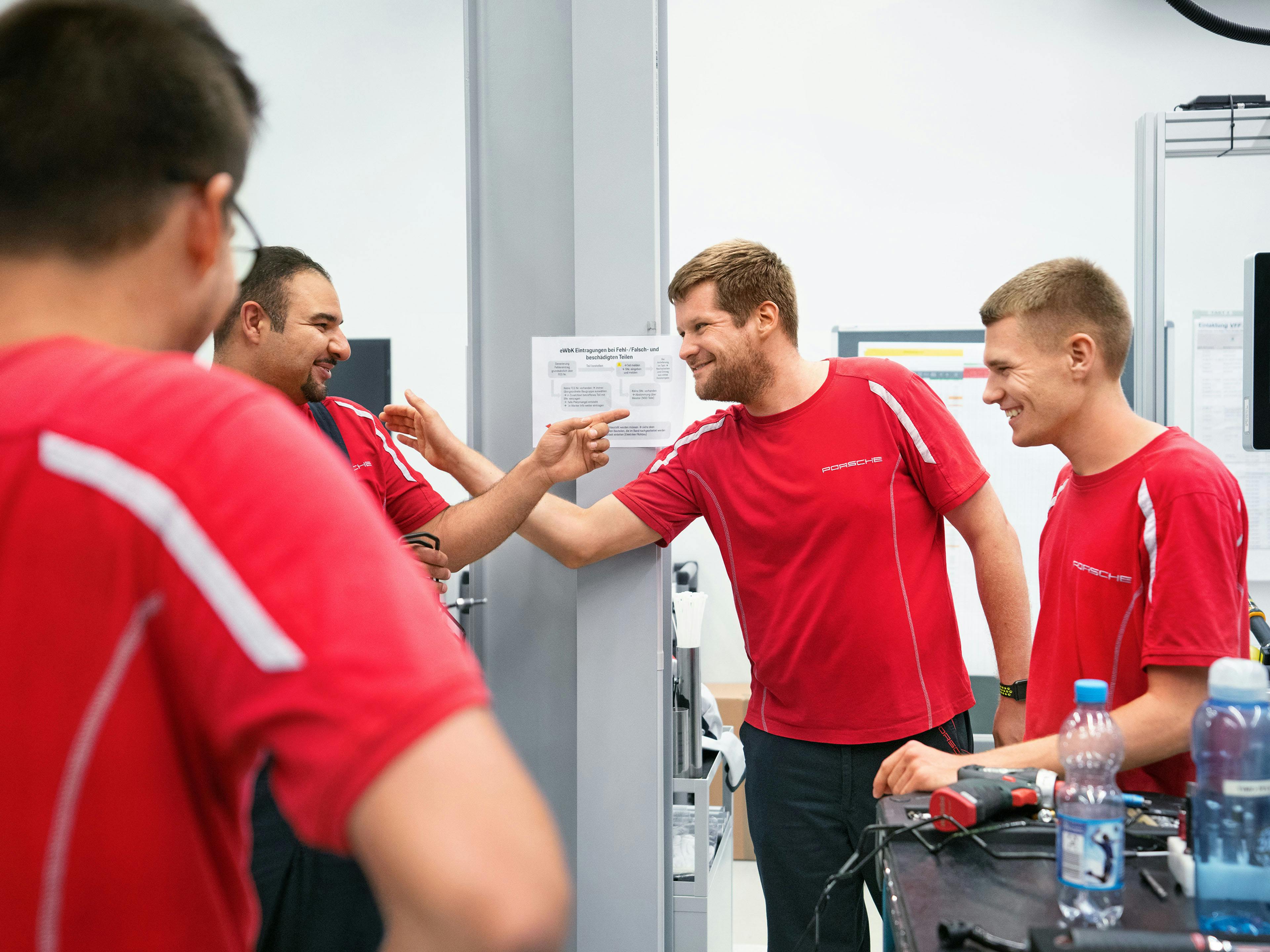 Vier gut gelaunte Porsche Mitarbeiter in roten T-shirts.