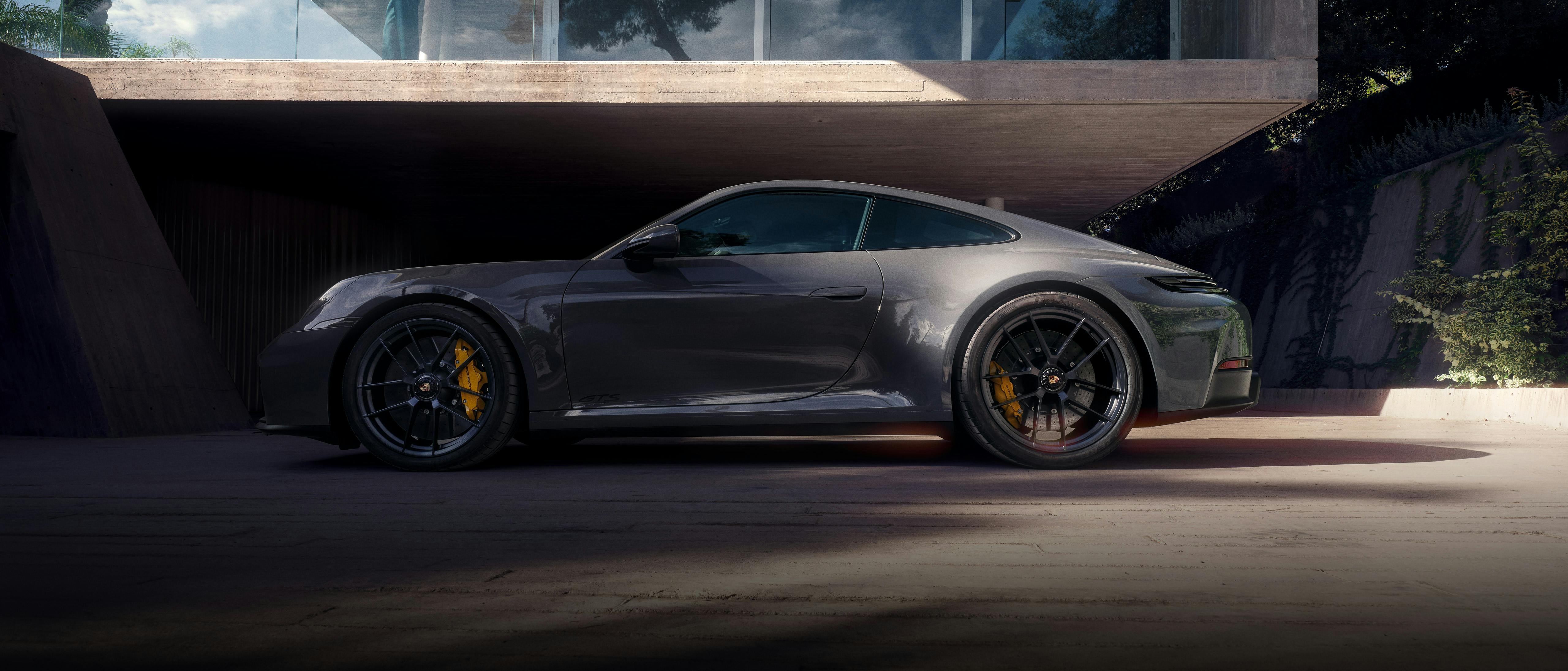 Una Porsche 911 argentata percorre una strada.