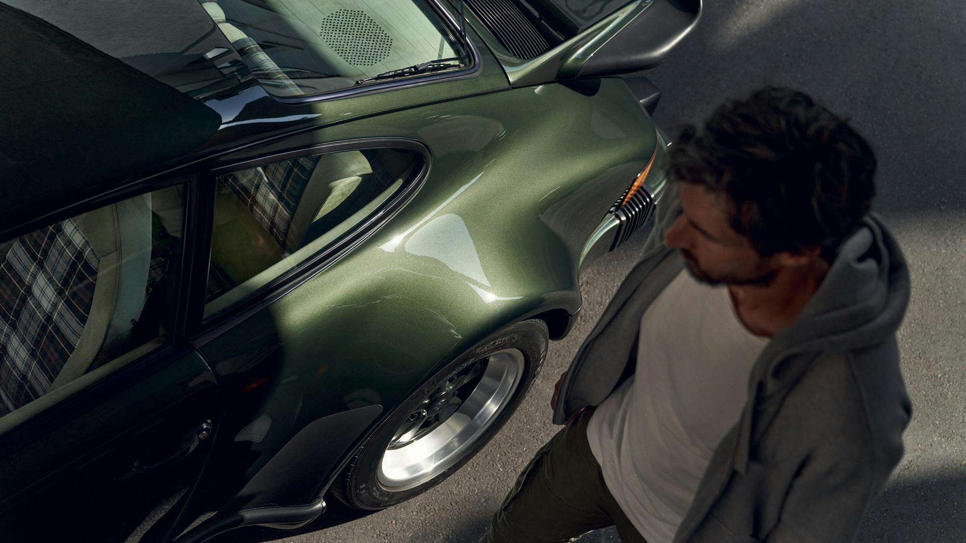 Mann steht neben einem dunkelgrünen Porsche 911 G-Modell.