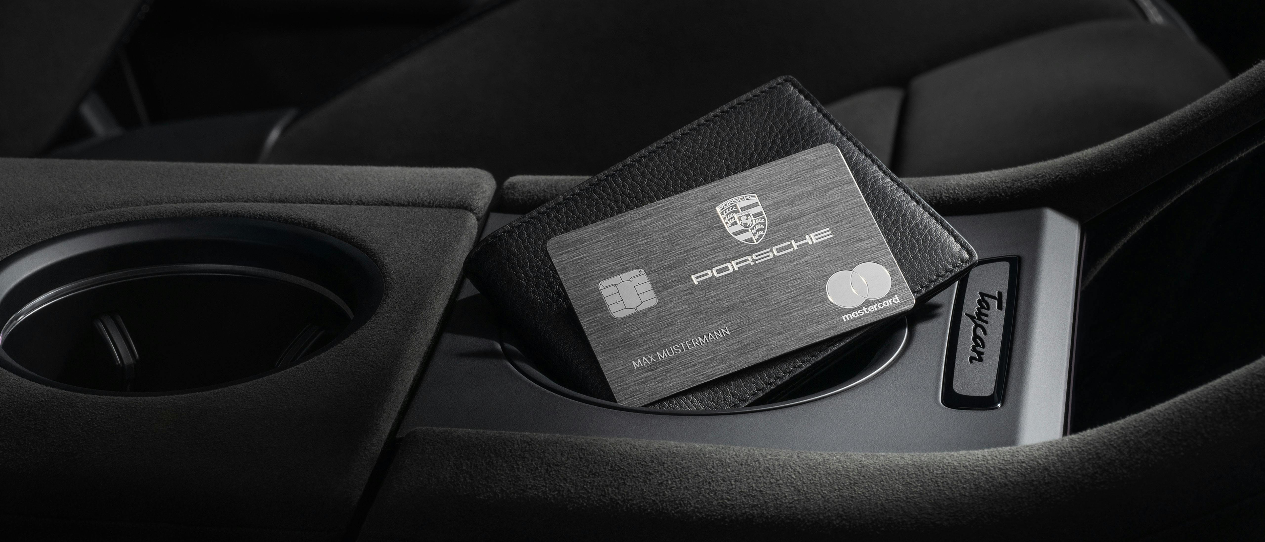 Die Porsche Mastercard liegt auf dem Portemonnaie in der Mittelkonsole eines Porsche Taycan.