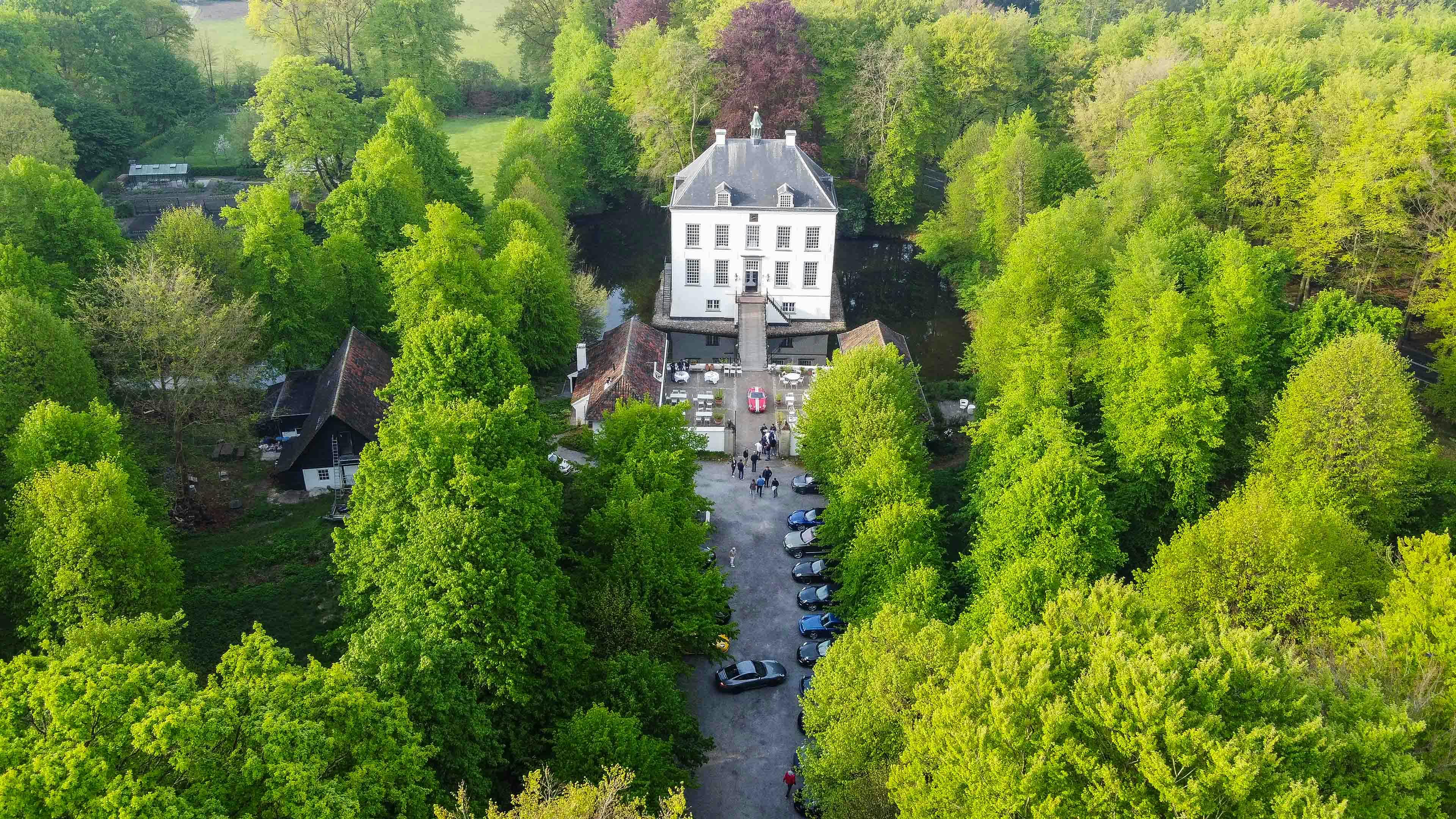 De Porsche rijders bij een luxe kasteel in een bosrijke omgeving aan de start van de Level Red Rally 2024