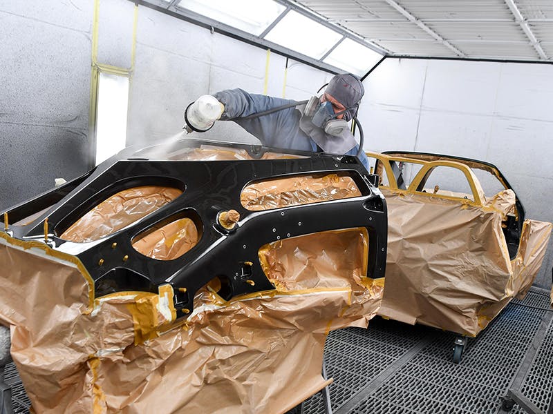 Employee of the Factory Restoration Atlanta painting a vehicle part.
