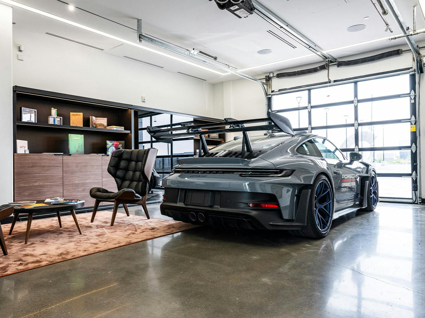 Une Porsche 911 GT3 RS grise garée dans une salle de livraison intérieure joliment aménagée.