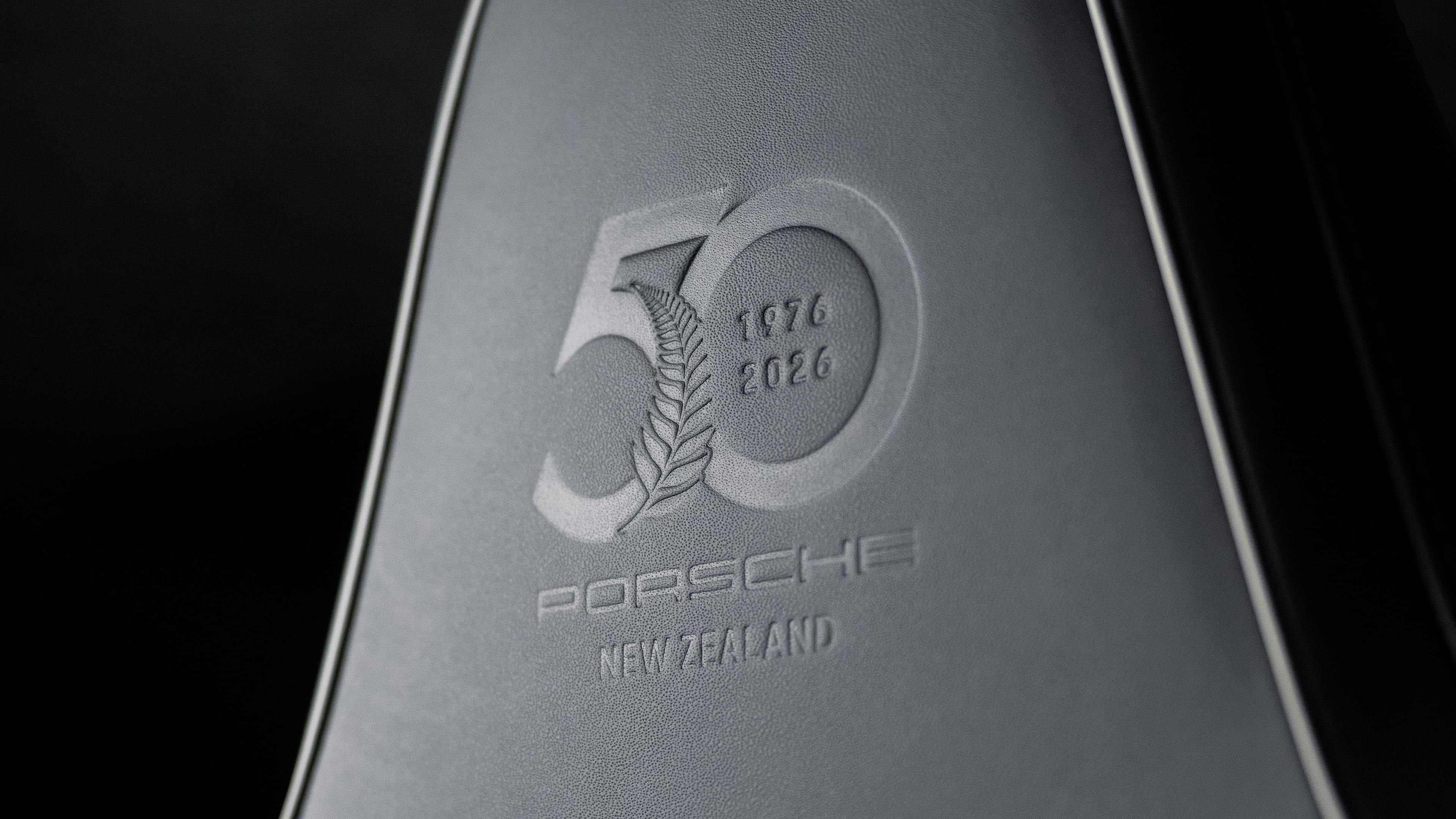 Close-up of a leather sports seat headrest embossed with a 50-year commemorative Porsche New Zealand logo.