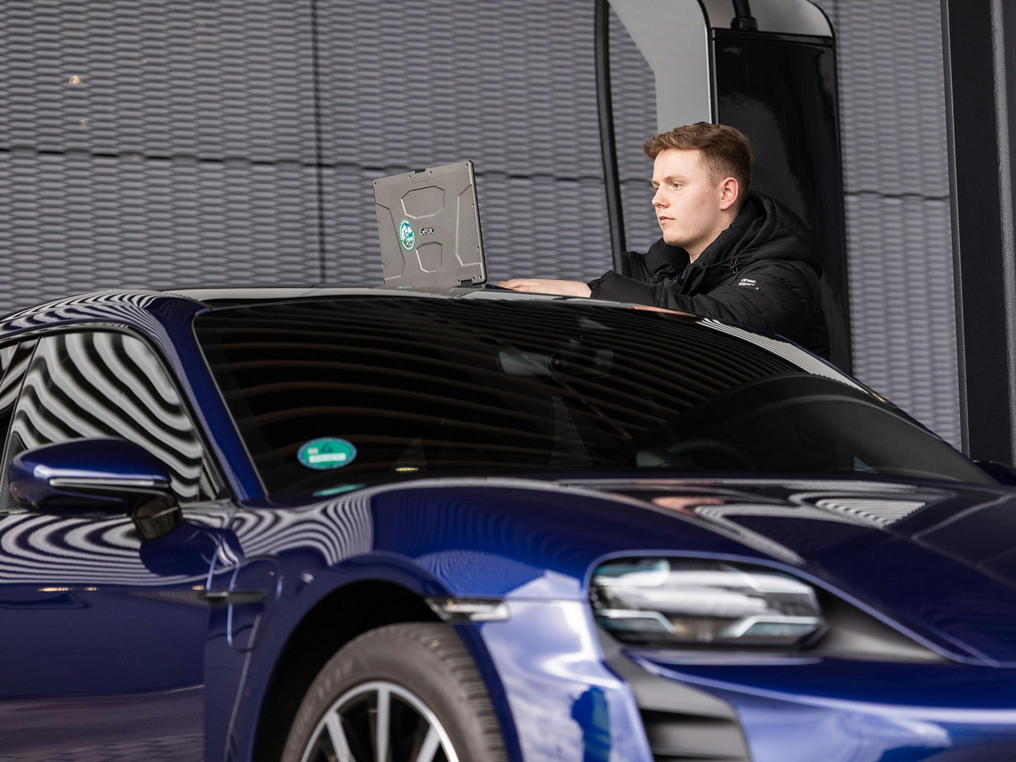 Der Porsche Mitarbeiter Tobias lächelt in die Kamera und bewegt sich in seinem Büro.
