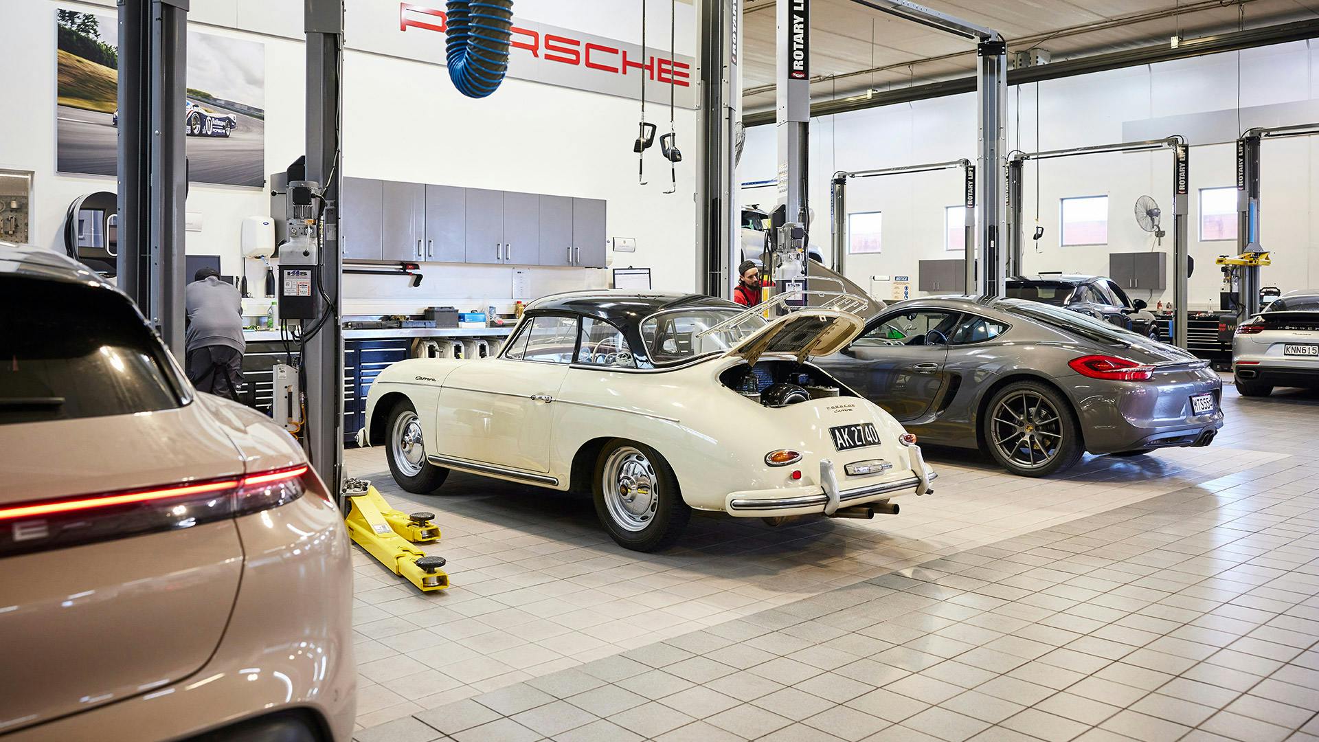 Line-up of new and classic Porsches in service workshop.