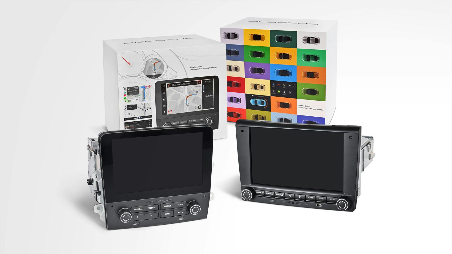 Two Porsche Classic Communication Management (PCCM) infotainment systems displayed in front of their product packaging, featuring touchscreen navigation and multimedia functionality for classic Porsche vehicles.