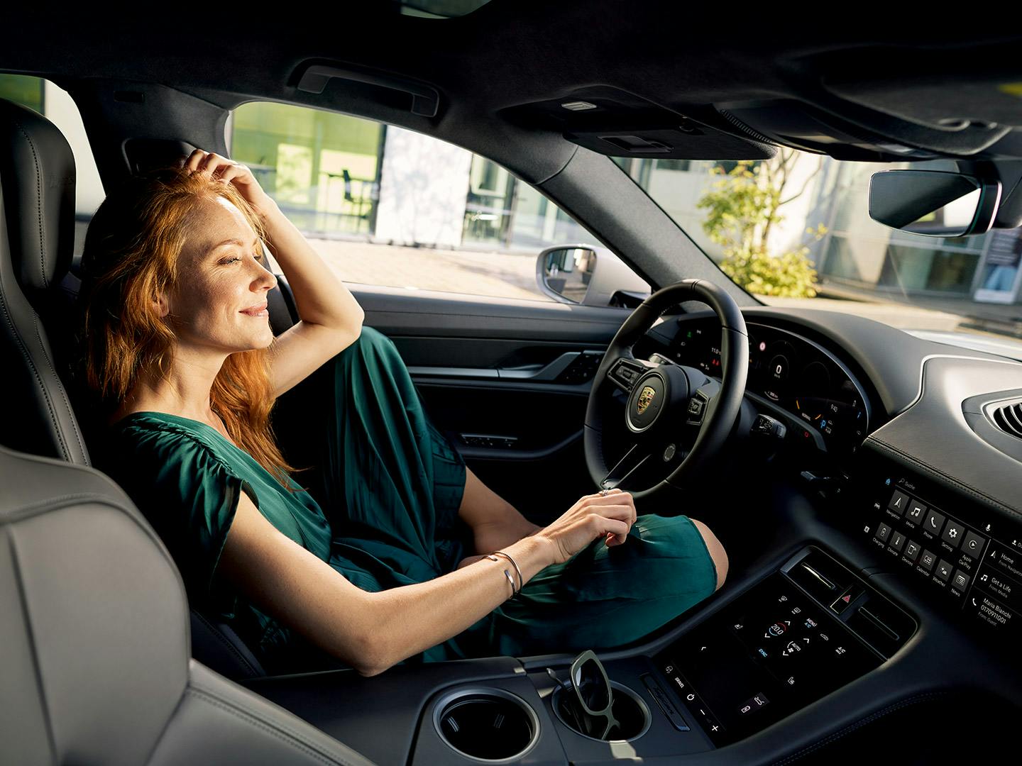Dos mujeres, conductora y copiloto, sonriendo mientras conducen un Porsche.