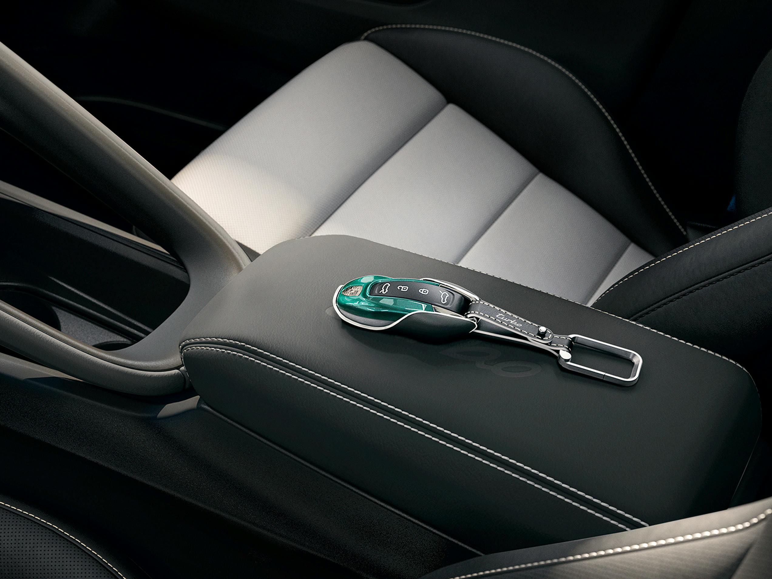 Clé personnalisée avec étui de Porsche Exclusive Manufaktur pour le Macan, posée sur l'accoudoir central.