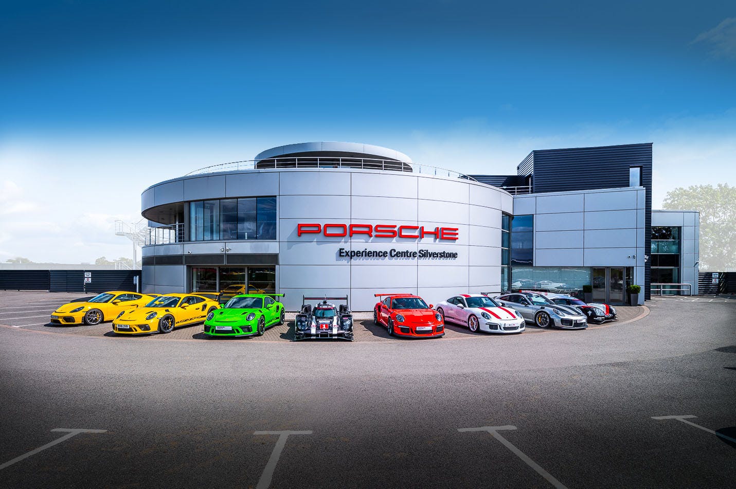 A range of Porsche cars parked in front of the Porsche Experience Centre Silverstone.