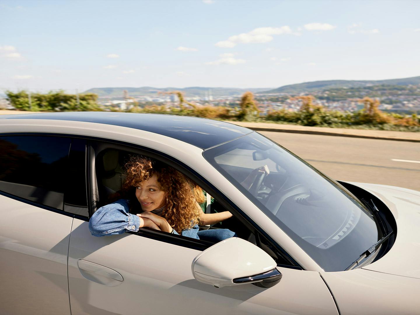 Two women on a road trip in a light grey Porsche Taycan.