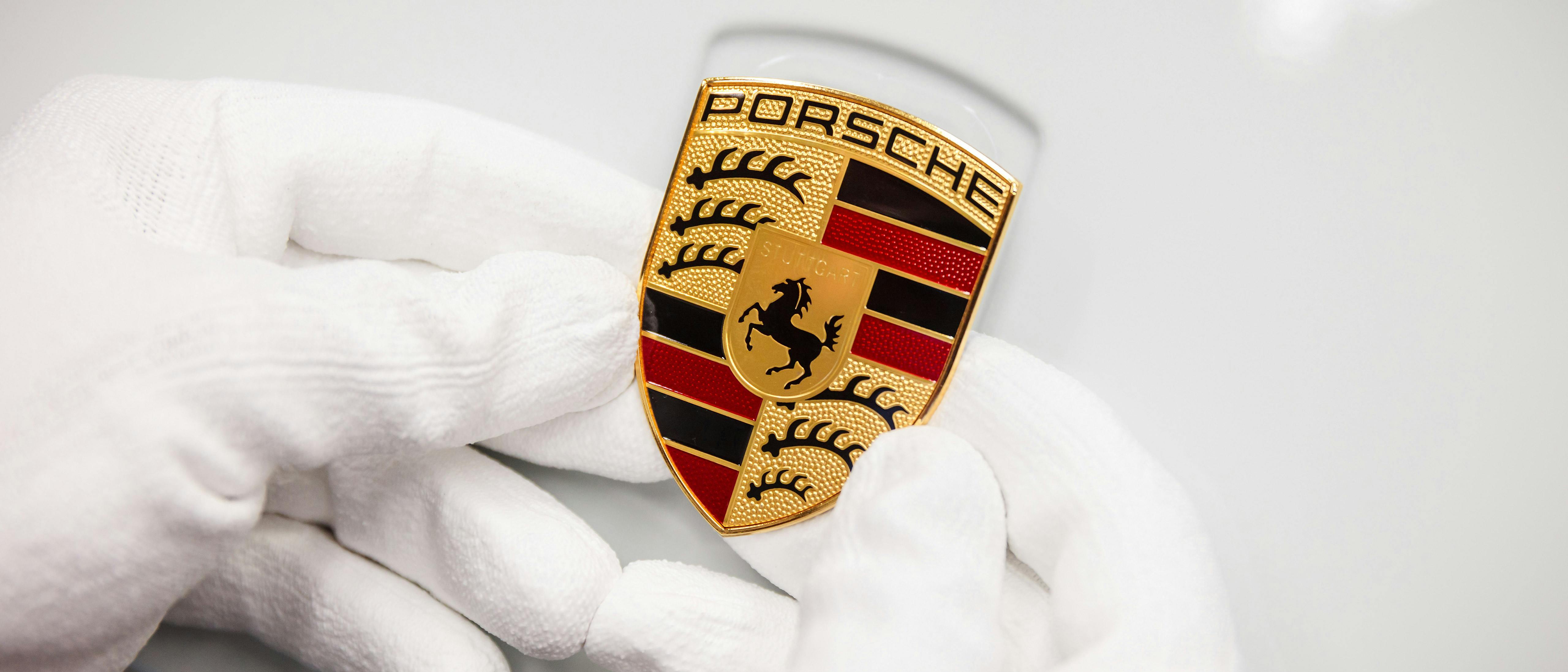 Hands in white gloves hold the Porsche Crest.