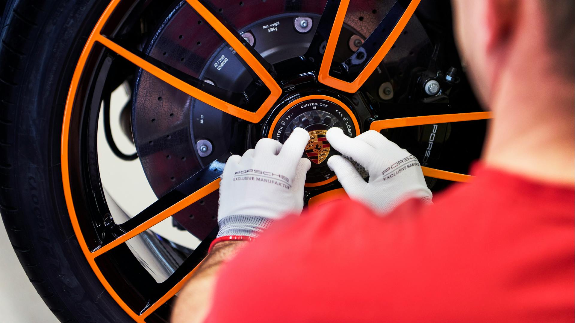 Dreams in Colours: Man hand in white glove fixes the rim wheel of  a 911 model from the 30 Years Porsche Thailand Edition.