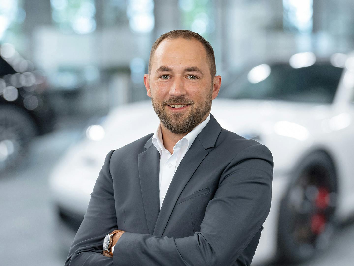 Porsche Mitarbeiterin berät einen Kunden der in einem Porsche Fahrzeug sitzt.