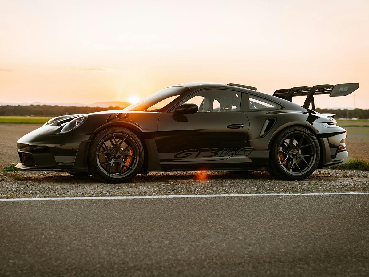 A GT3 RS coloured in Slategrey6601 with accents in Gunmetal Grey from the left side standing on the side of a road in sunrise.