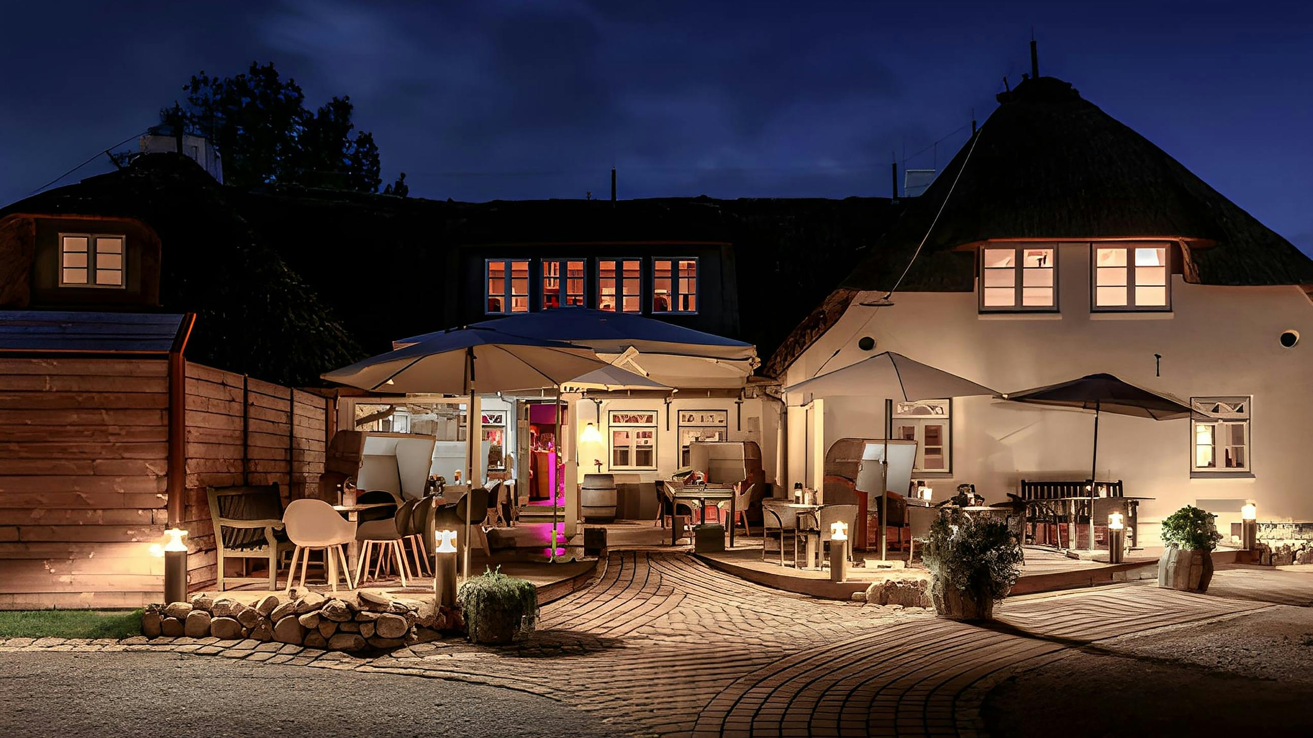 Blick von vorne auf das Landhaus Stricker mit Beleuchtung am Abend.
