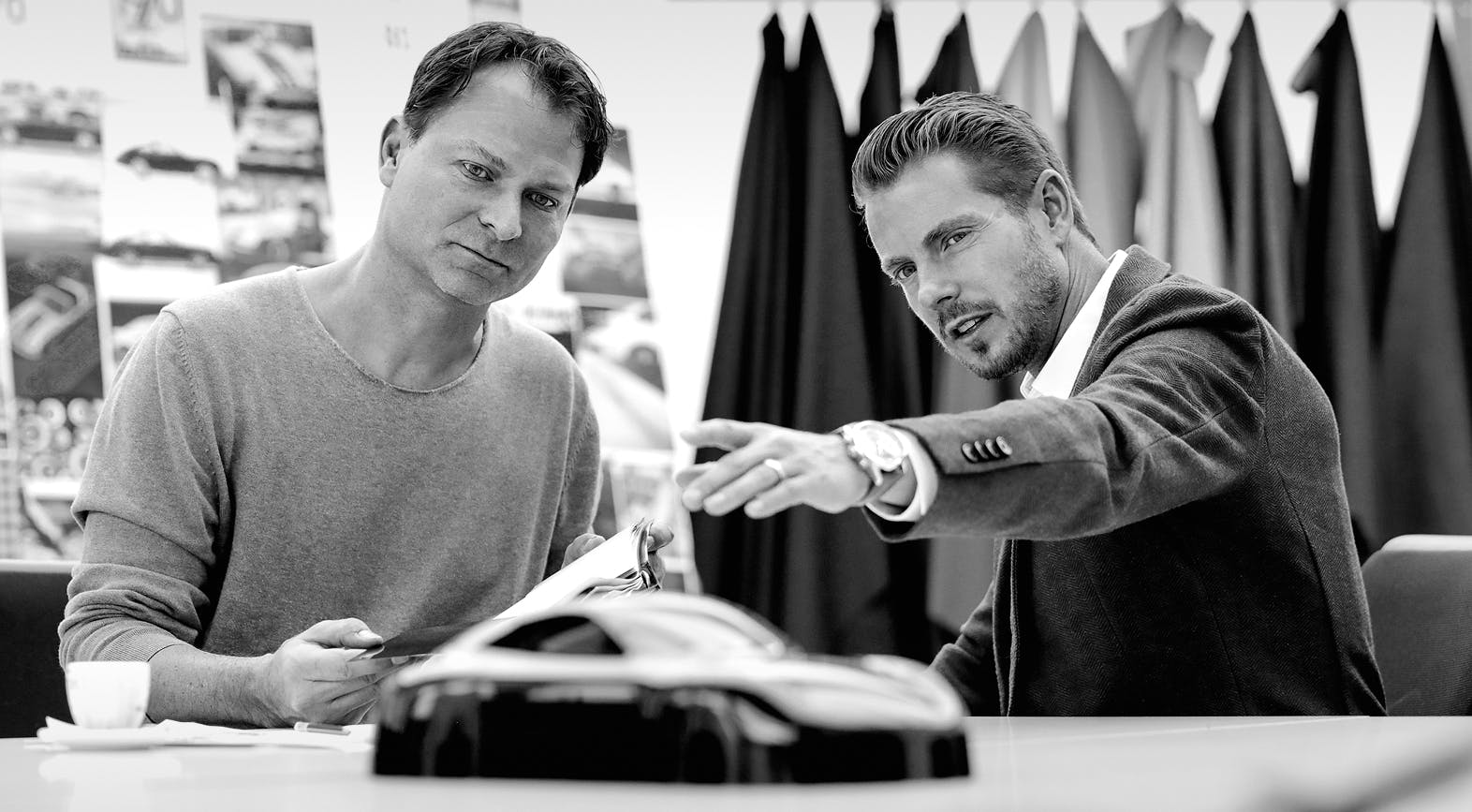 Two men are discussing the design of a Porsche. Black and white photo.