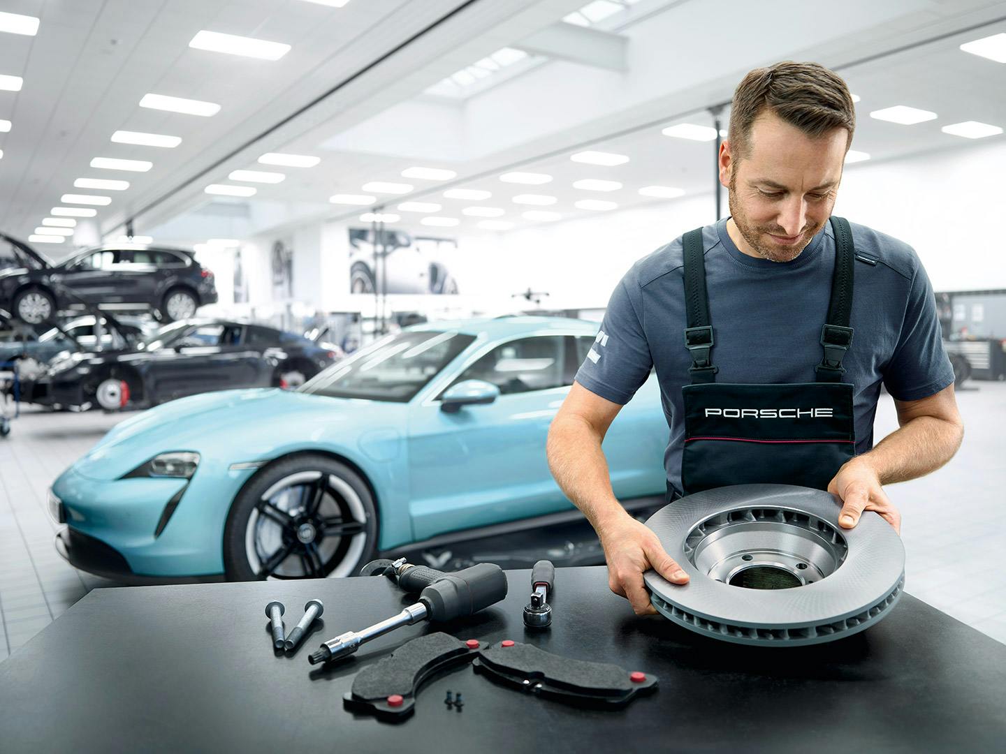 Mecánico revisando los frenos en un taller Porsche.