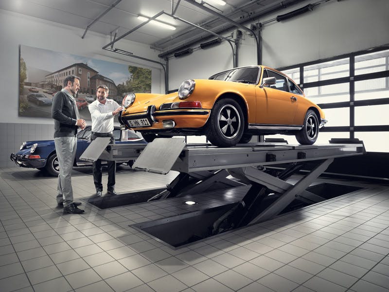 Vehículo Porsche Classic en color amarillo elevado como parte de una revisión en el taller.